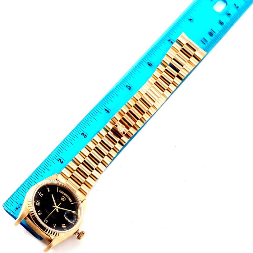 The image shows a Rolex President 18238 Men's Yellow Gold Black Dial 18238 Men's Yellow Gold Black Dial model watch laid flat alongside a blue ruler for measurement.