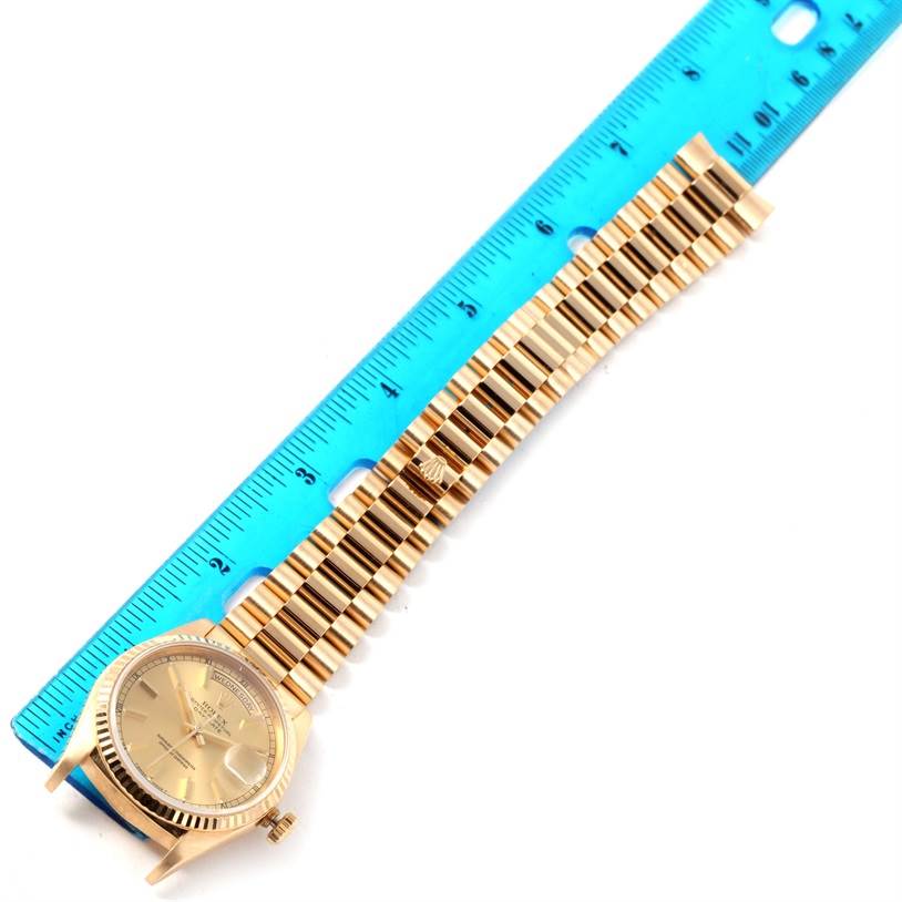 The image shows a Rolex President 18238 Men
s Yellow Gold Champagne Dial 18238 Men
s Yellow Gold Champagne Dial model watch laid flat next to a blue ruler, displaying the face and entire band.