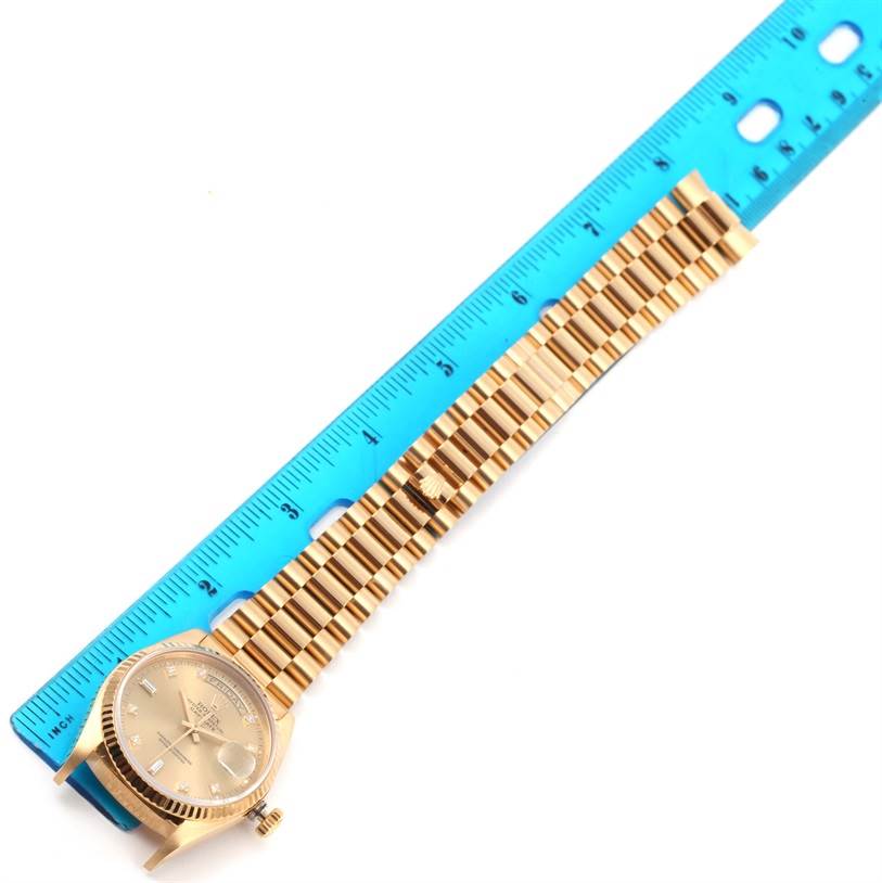 This image shows a top-down view of a Rolex President 18038 Men
s Yellow Gold Champagne Dial 18038 Men
s Yellow Gold Champagne Dial model watch with its band aligned against a blue ruler for measurement.