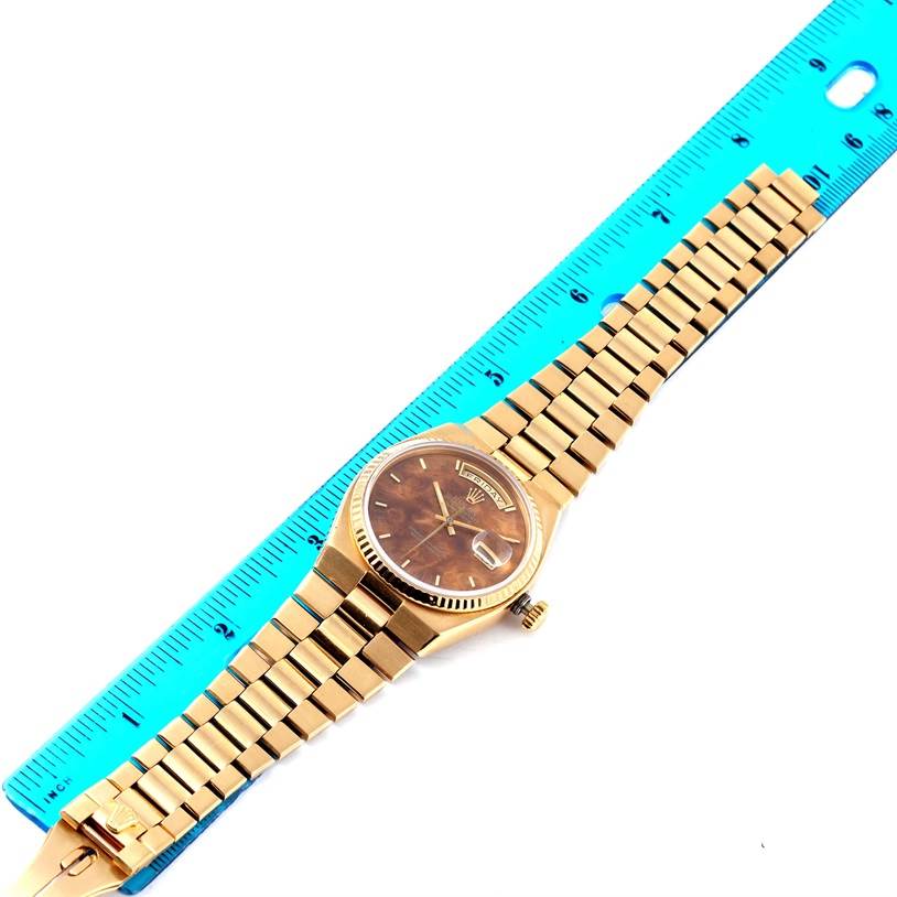 The image shows a top-down view of a Rolex President 19018 Men's Yellow Gold Brown Dial 19018 Men's Yellow Gold Brown Dial model watch placed beside a blue ruler.