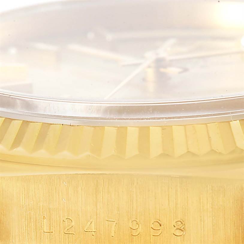 This close-up image shows the serial number, bezel, and a portion of the crystal of a Rolex President 18238 Men
s Yellow Gold Champagne Dial 18238 Men
s Yellow Gold Champagne Dial model watch.