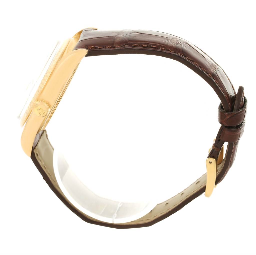 A side view of a Rolex President 1601 Men
s Yellow Gold White Dial 1601 Men
s Yellow Gold White Dial model watch is shown with its case, crown, and brown leather strap with a buckle.