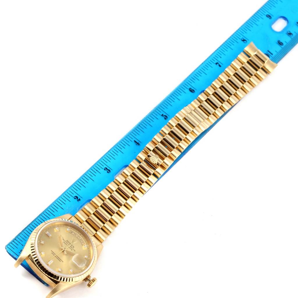 The image shows a Rolex President 18238 Men
s Yellow Gold Champagne Dial 18238 Men
s Yellow Gold Champagne Dial watch laid flat alongside a blue ruler, displaying the face and entire strap.