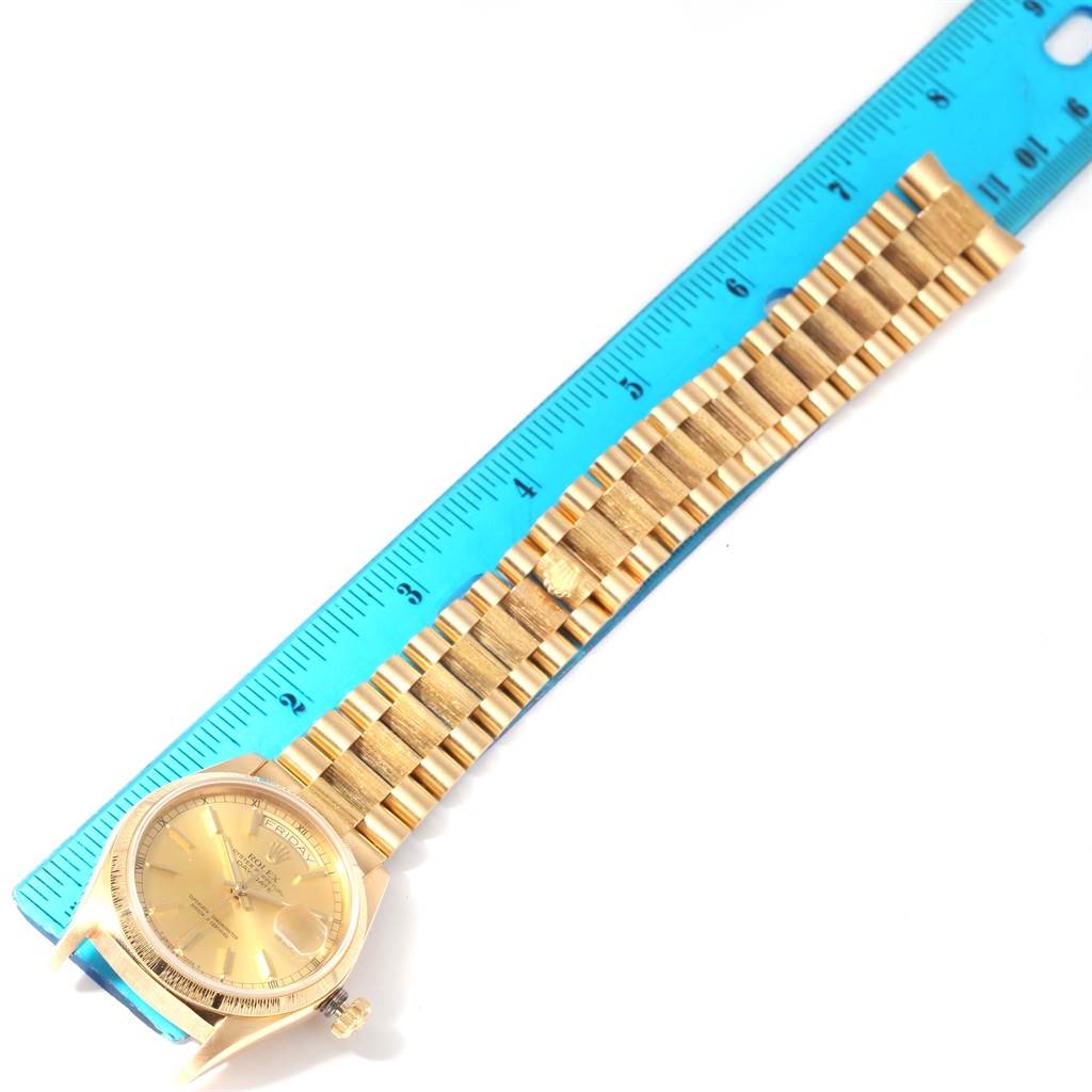 The image shows a Rolex President 18078 Men
s Yellow Gold Champagne Dial 18078 Men
s Yellow Gold Champagne Dial model watch laid flat next to a ruler, displaying its face and full bracelet.