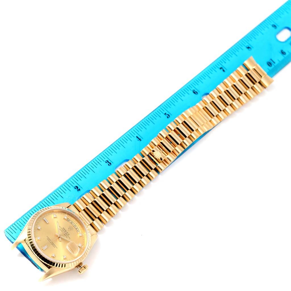 The image shows a Rolex President 18238 Men
s Yellow Gold Champagne Dial 18238 Men
s Yellow Gold Champagne Dial model watch laid flat next to a ruler, highlighting the face, case, and bracelet.