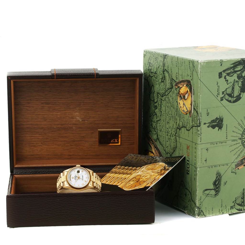 The image shows a Rolex President 18078 Men
s Yellow Gold White Dial 18078 Men
s Yellow Gold White Dial model watch placed in an open wooden box with a green outer box beside it.