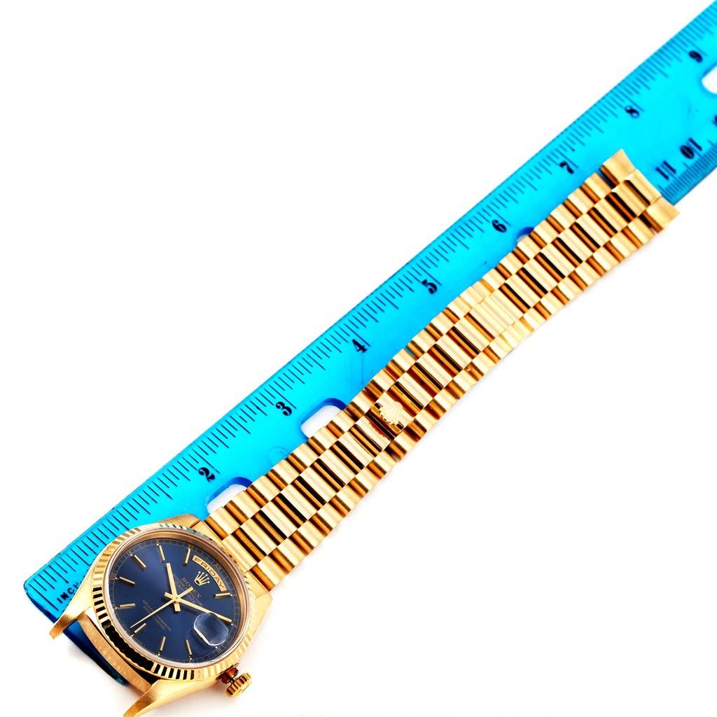 The image shows a Rolex President 18238 Men's Yellow Gold Blue Dial 18238 Men's Yellow Gold Blue Dial watch with its case, dial, and full bracelet laid next to a blue ruler.