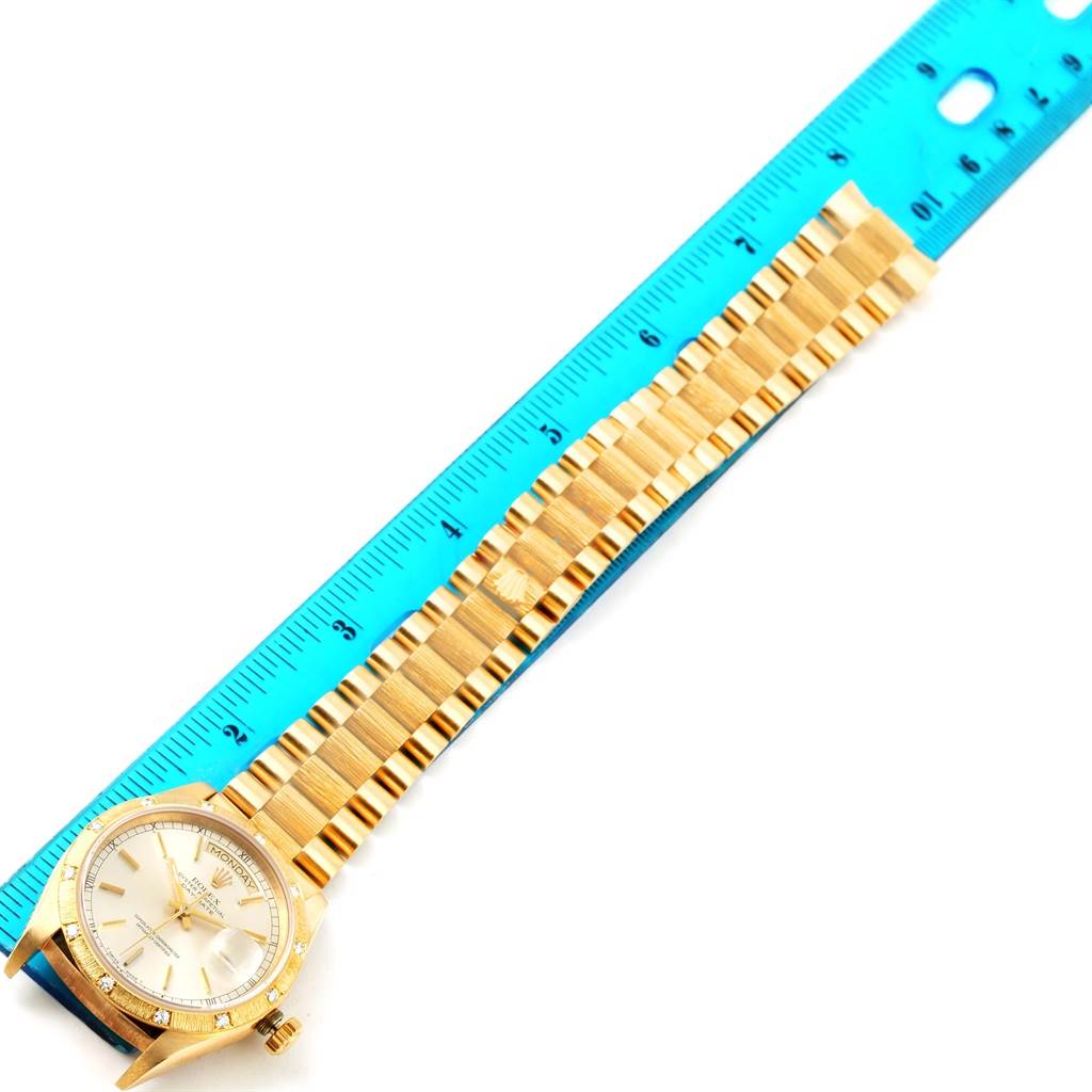 The image shows the Rolex President 18078 Men
s Yellow Gold Silver Dial 18078 Men
s Yellow Gold Silver Dial model watch from a top view, focusing on its face and the bracelet measured against a blue ruler.