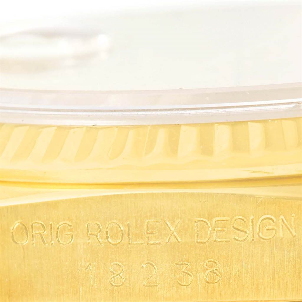 This close-up image shows the side of a Rolex President 18238 Men
s Yellow Gold Champagne Dial 18238 Men
s Yellow Gold Champagne Dial model watch with "ORIG ROLEX DESIGN" and the model number engraved on the case.