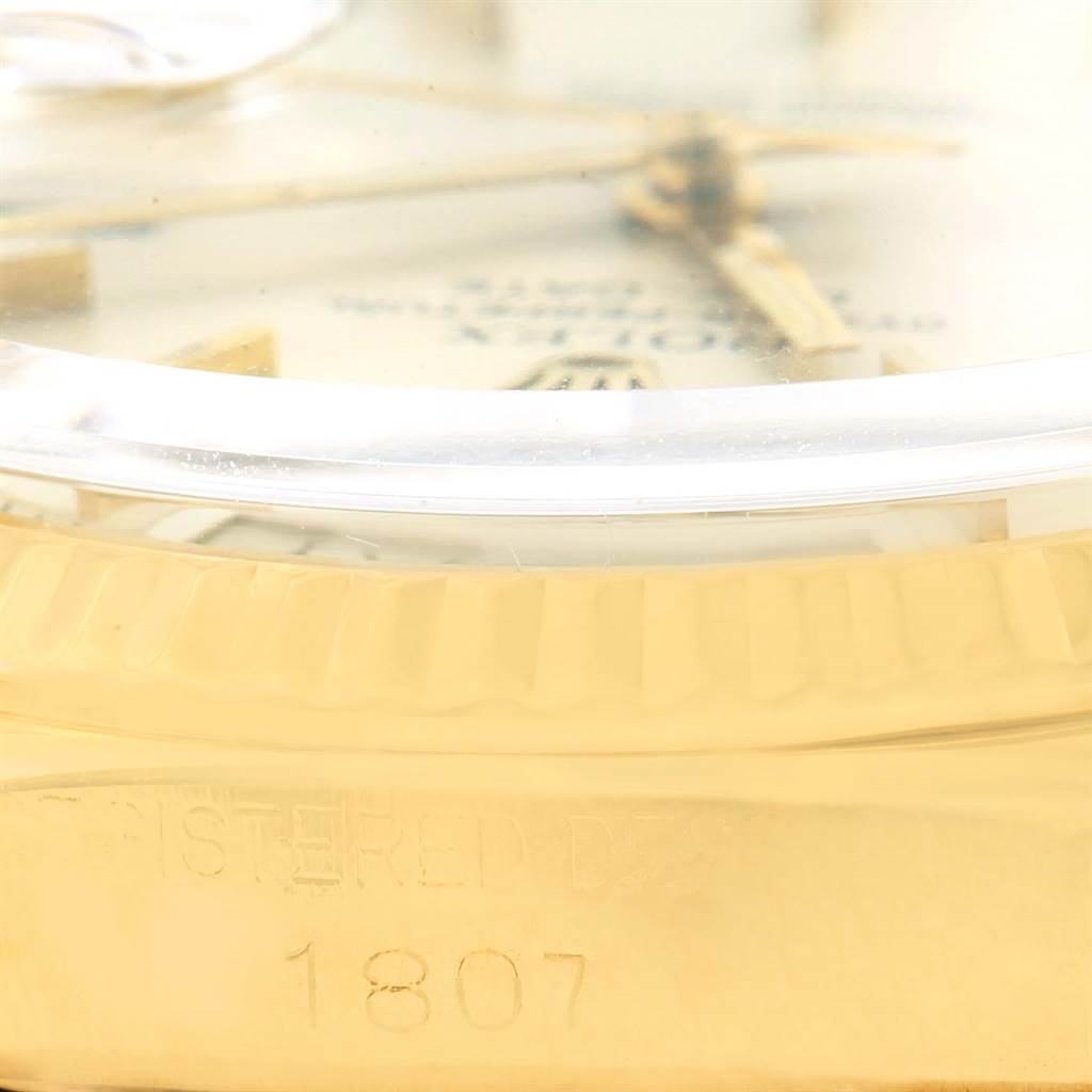 Close-up of a Rolex President 1803 Men's Yellow Gold Silver Dial 1803 Men's Yellow Gold Silver Dial model watch showing part of the bezel, dial, and case with the model number 1807 engraved.