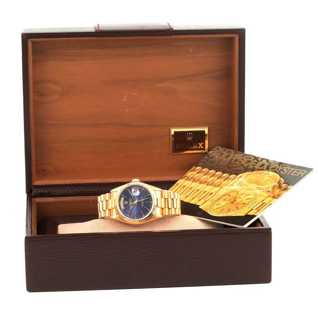 The image shows a Rolex President 18038 Men
s Yellow Gold Blue Dial 18038 Men
s Yellow Gold Blue Dial model watch with a blue dial and gold bracelet, displayed in its box with accompanying booklets.