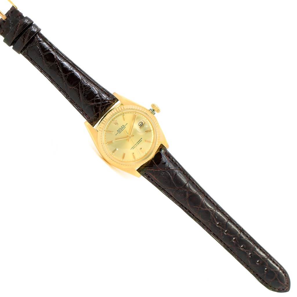 The Rolex President 1601 Men's Yellow Gold Champagne Dial 1601 Men's Yellow Gold Champagne Dial model watch is shown with a gold bezel, dial, and a dark brown leather strap, viewed from above.