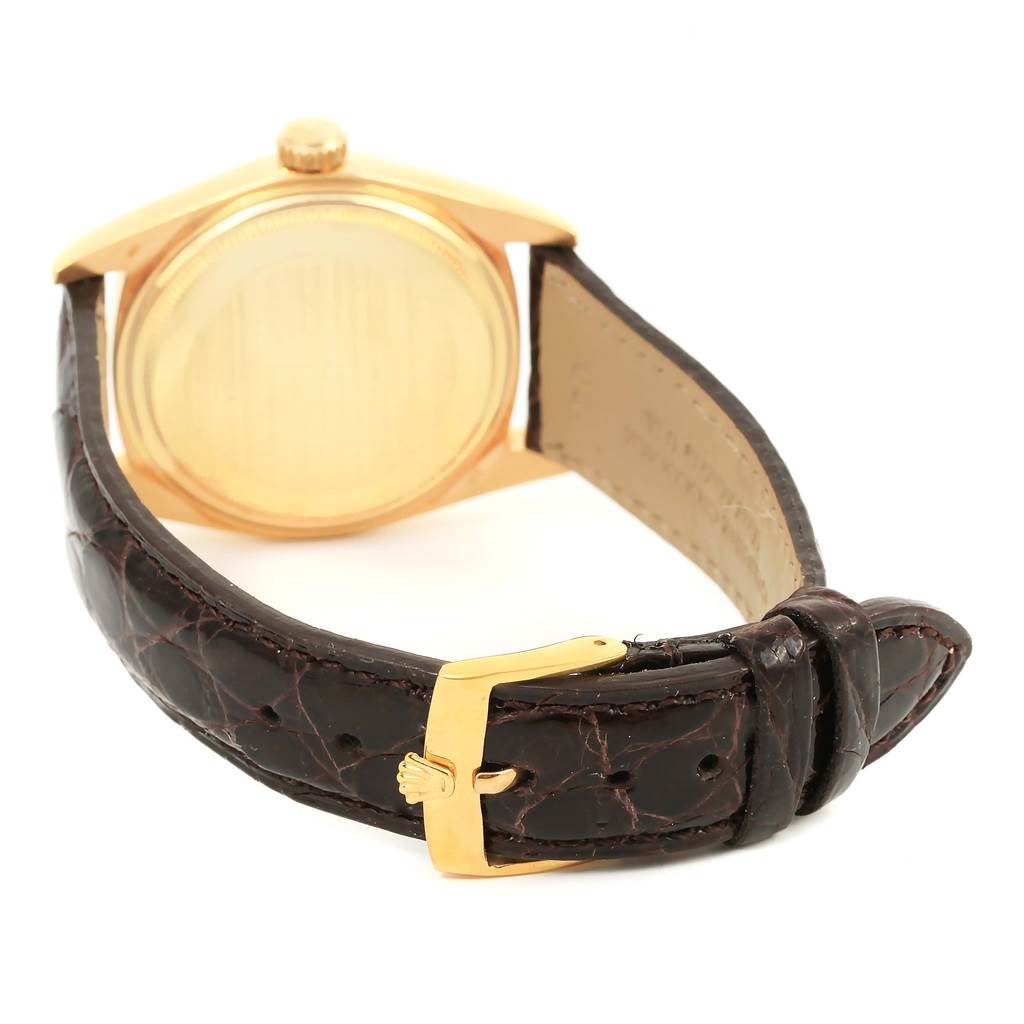 The image shows the back of a Rolex President 1601 Men's Yellow Gold Champagne Dial 1601 Men's Yellow Gold Champagne Dial model watch and its leather strap with a gold buckle.