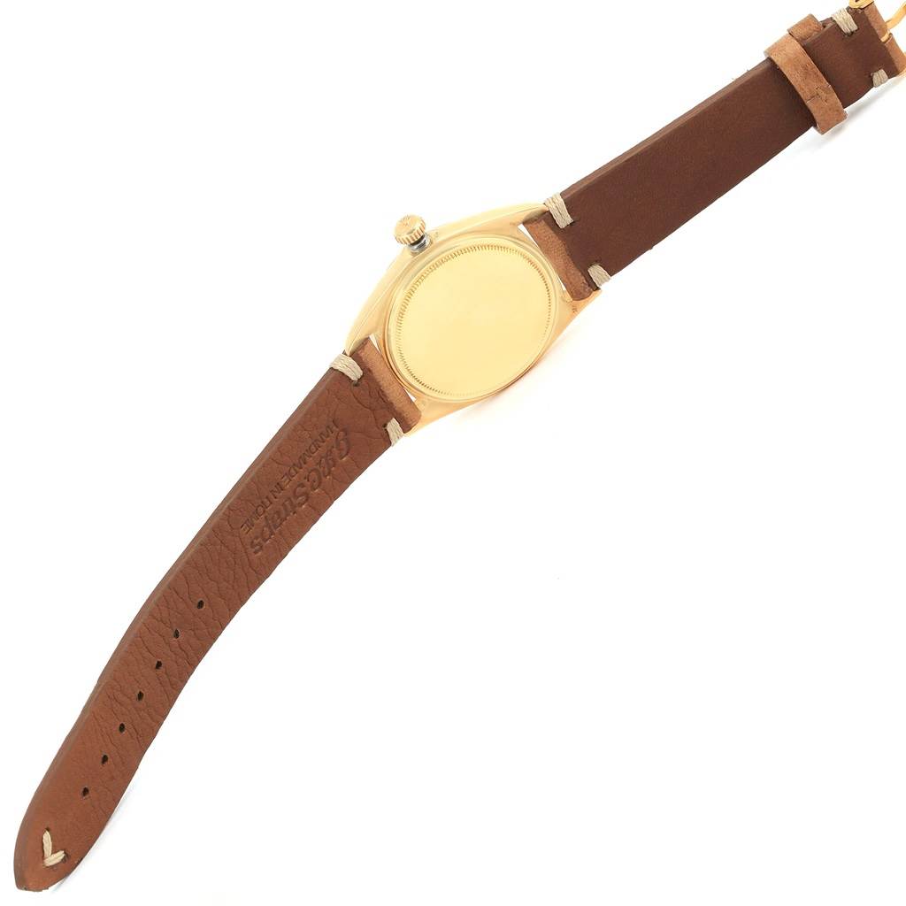 The image shows the back of a Rolex President 1803 Men
s Yellow Gold Champagne Dial 1803 Men
s Yellow Gold Champagne Dial model watch with a brown leather strap lying flat.