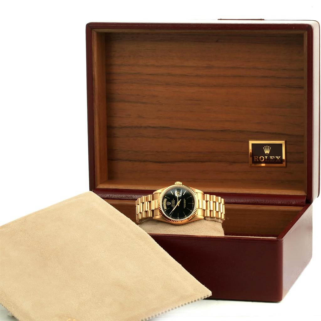 The image shows a Rolex President 18238 Men
s Yellow Gold Black Dial 18238 Men
s Yellow Gold Black Dial model watch resting in an open wooden Rolex box with a beige cloth partially covering it.