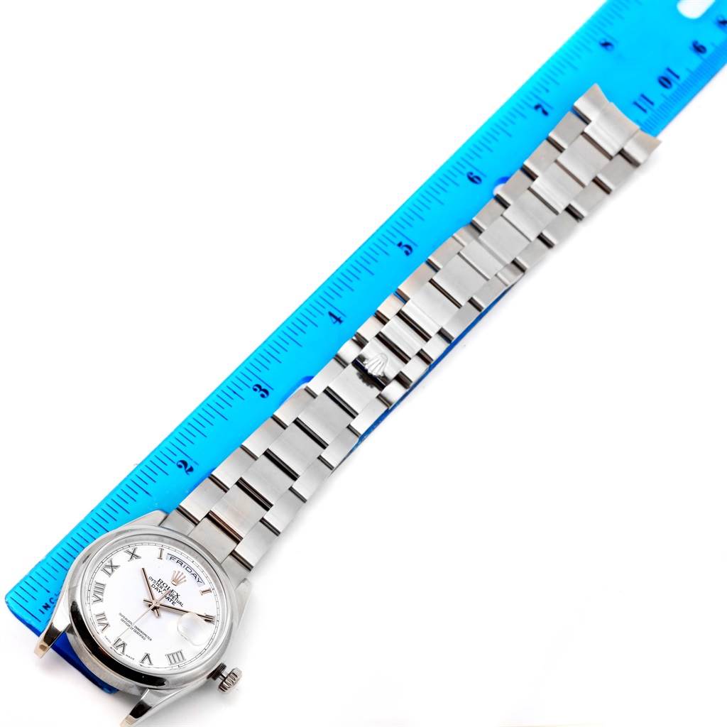 This image shows a Rolex President 118209 Men's White Gold White Dial 118209 Men's White Gold White Dial model watch laid flat with a blue ruler measuring its length.