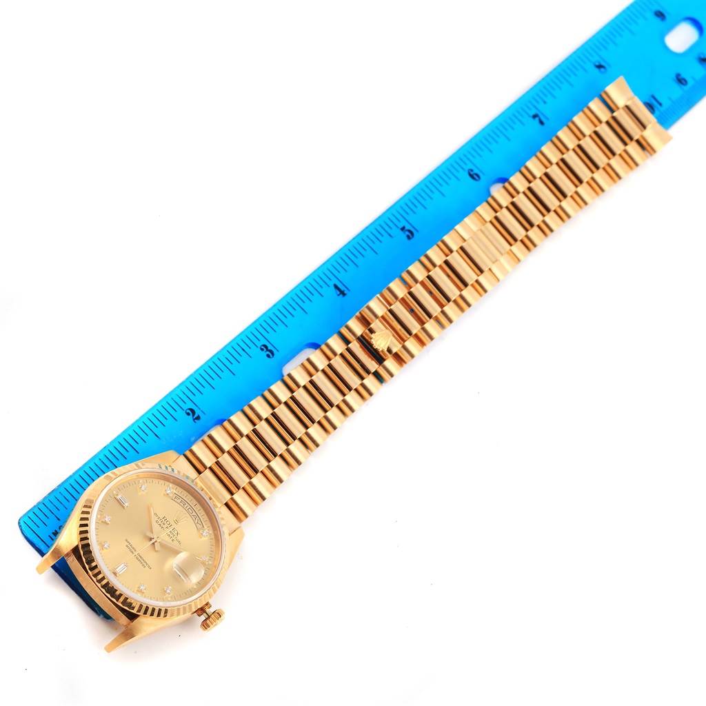 The Rolex President 18238 Men's Yellow Gold Champagne Dial 18238 Men's Yellow Gold Champagne Dial model watch is shown laid flat with its dial and bracelet visible, measured against a blue ruler.