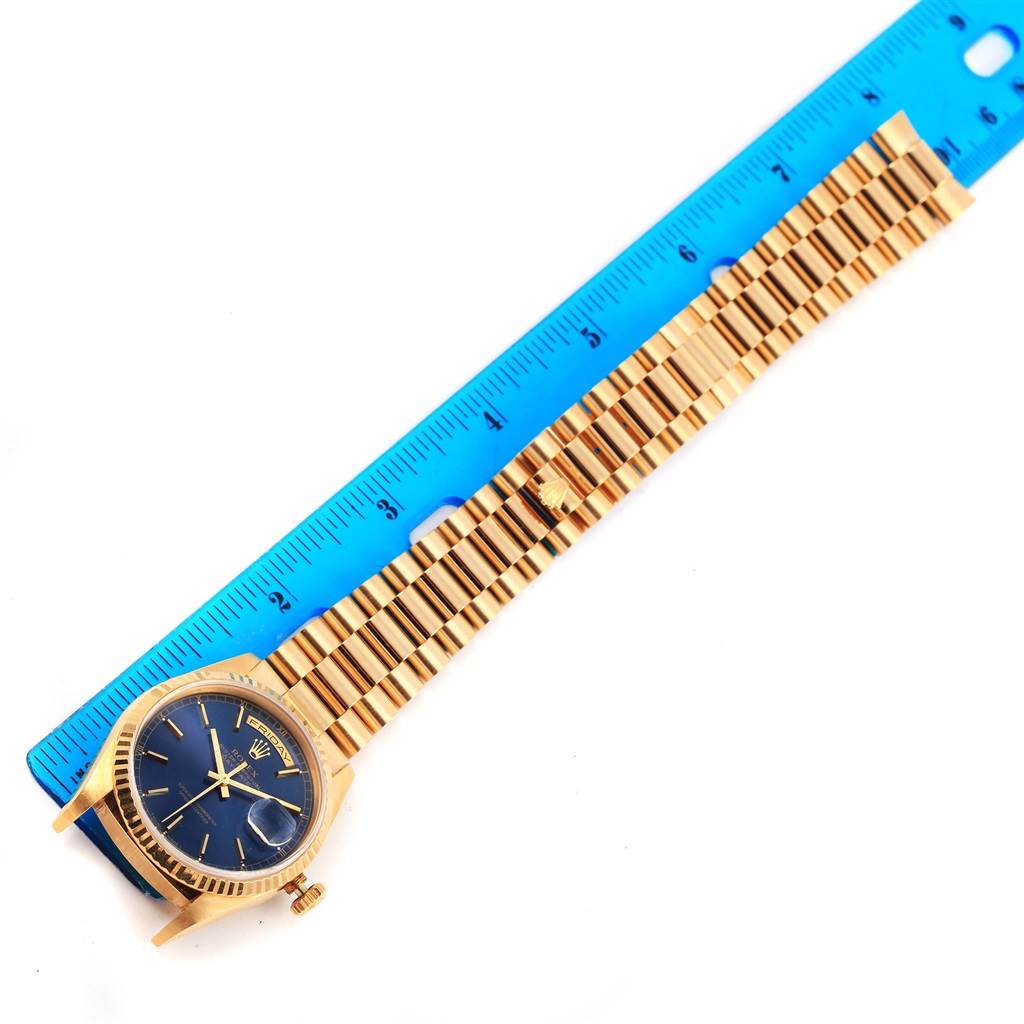 The image shows a gold Rolex President 18238 Men's Yellow Gold Blue Dial 18238 Men's Yellow Gold Blue Dial model watch with a blue dial face, lying next to a blue ruler for scale.