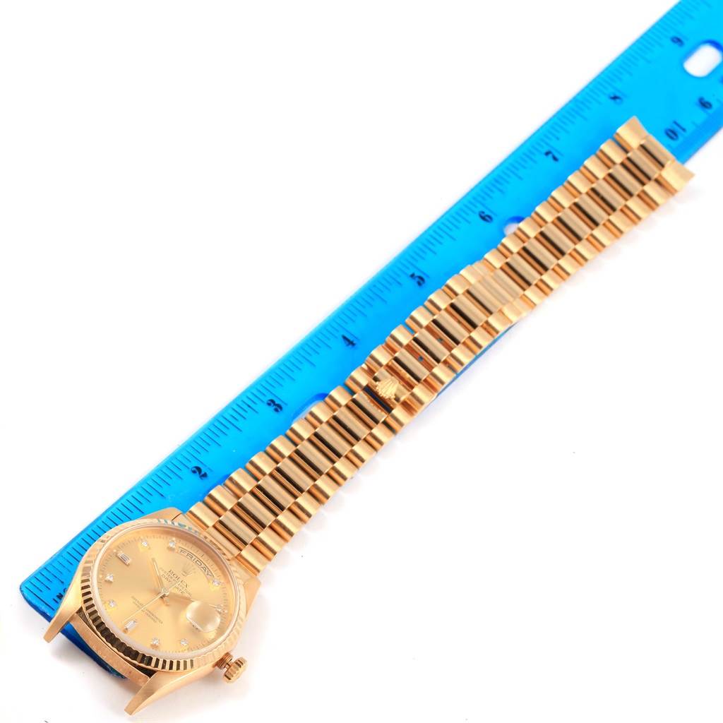 The Rolex President 18238 Men's Yellow Gold Champagne Dial 18238 Men's Yellow Gold Champagne Dial model watch is shown from the top, displaying its face, bezel, and full bracelet alongside a blue ruler.