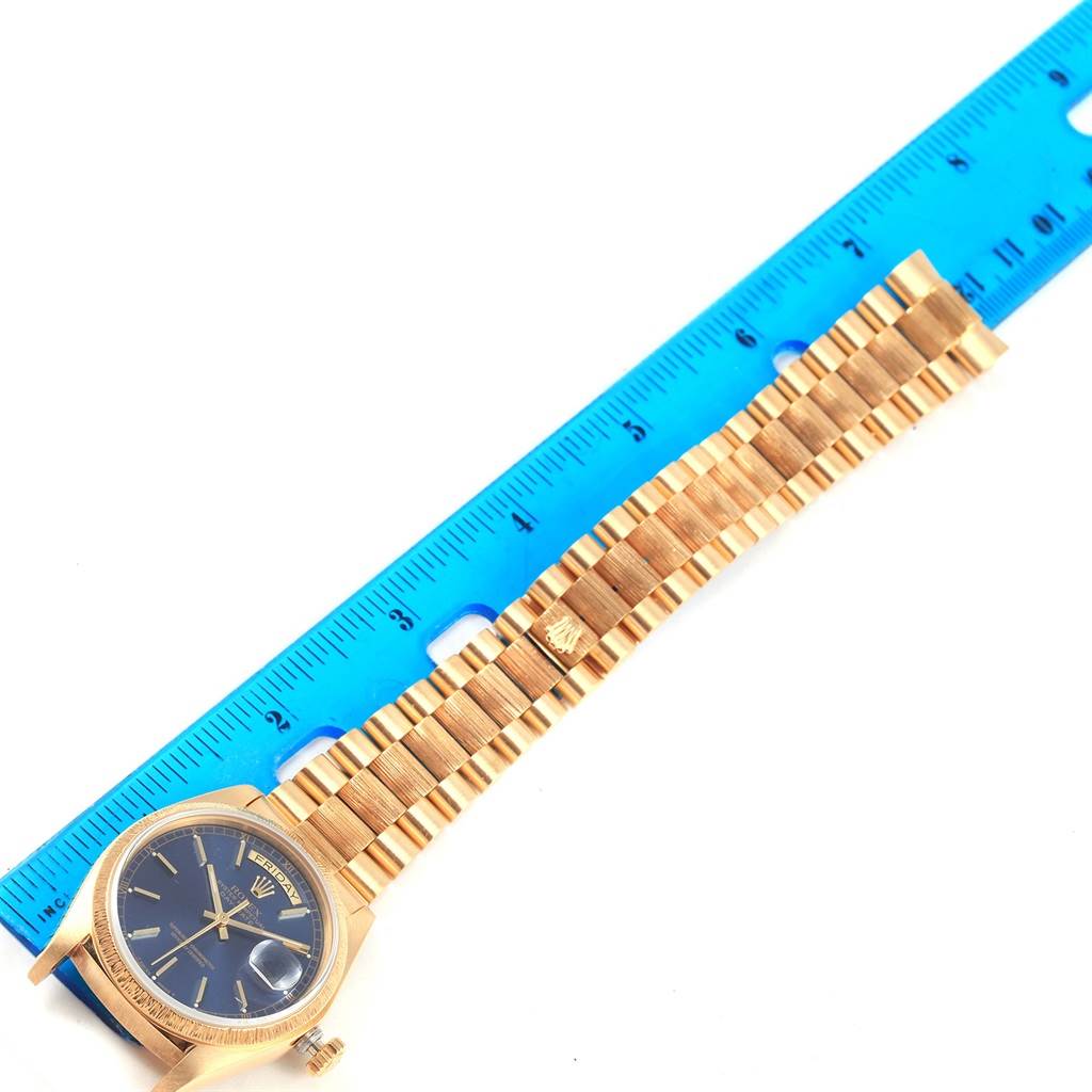 This image shows a Rolex President 18078 Men's Yellow Gold Blue Dial 18078 Men's Yellow Gold Blue Dial model watch laid flat with its bracelet alongside a blue ruler for scale.