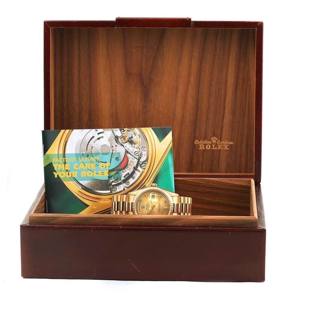 This image shows a Rolex President 18238 Men's Yellow Gold Champagne Dial 18238 Men's Yellow Gold Champagne Dial model watch in an open wooden box, with a care booklet placed behind it.