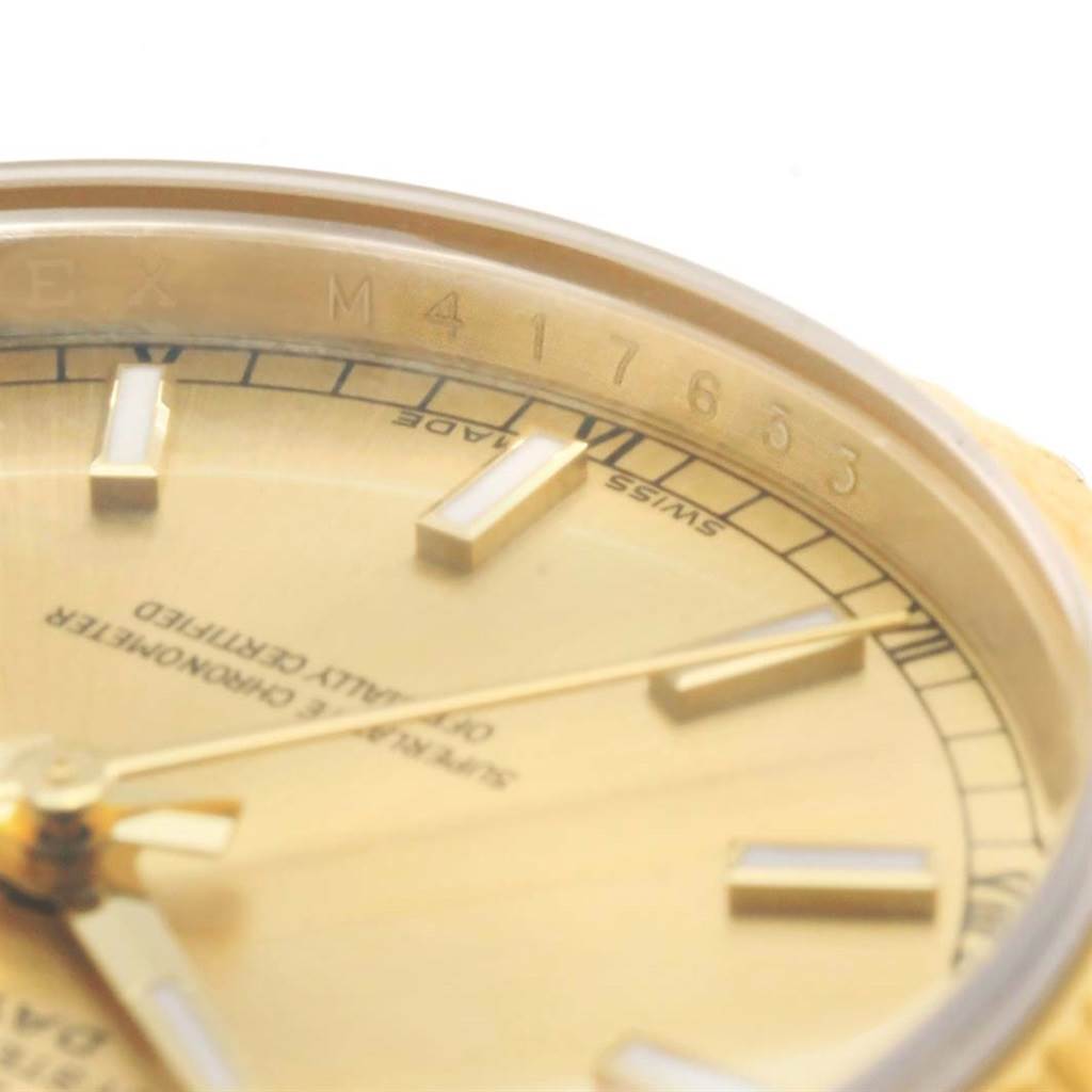 This close-up image of a Rolex President 118238 Men's Yellow Gold Champagne Dial 118238 Men's Yellow Gold Champagne Dial watch shows part of the gold dial, markers, and the serial number engraved on the rim.