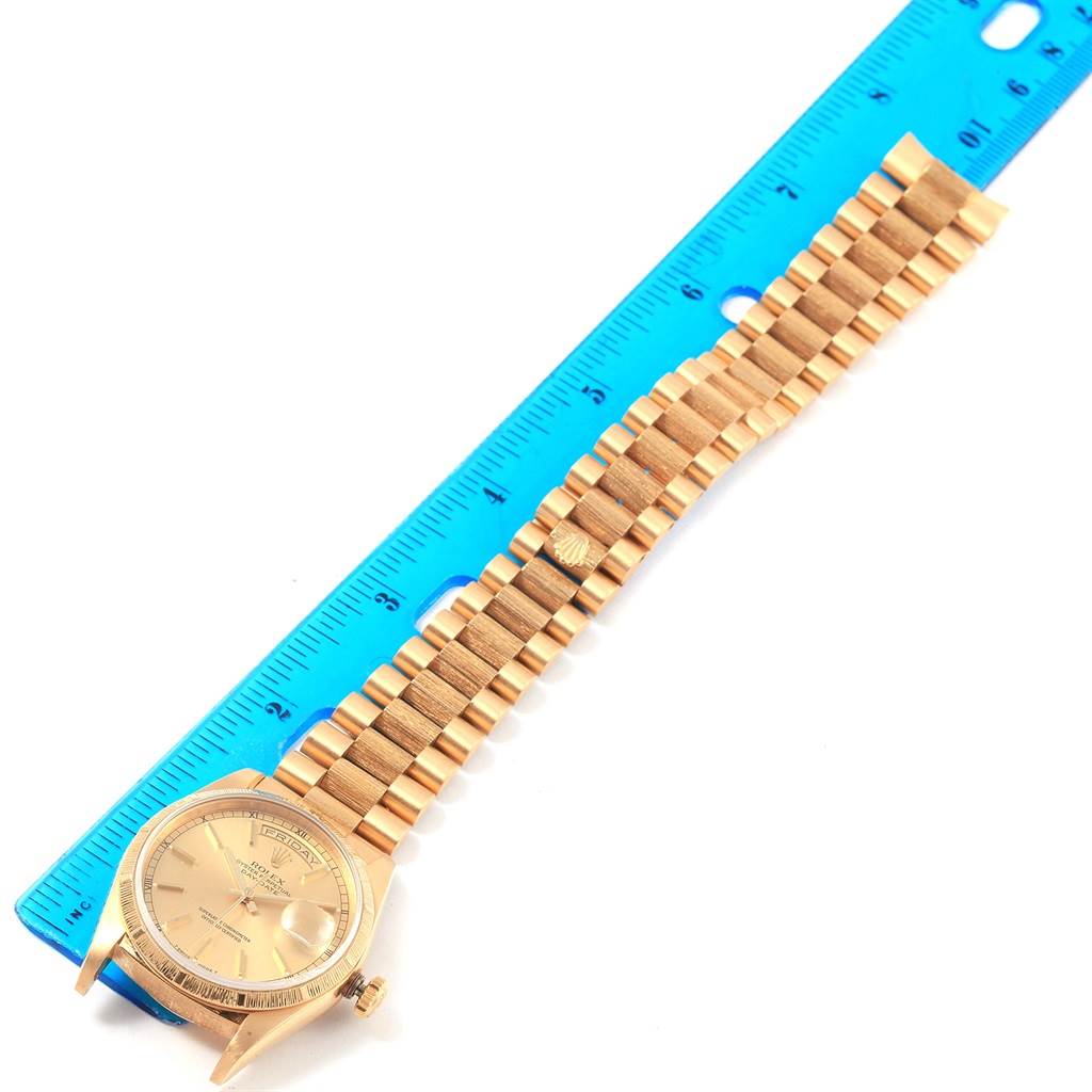 The photo shows the Rolex President 18248 Men
s Yellow Gold Champagne Dial 18248 Men
s Yellow Gold Champagne Dial model watch from a top view, displaying its dial, bezel, and full bracelet alongside a ruler for scale.