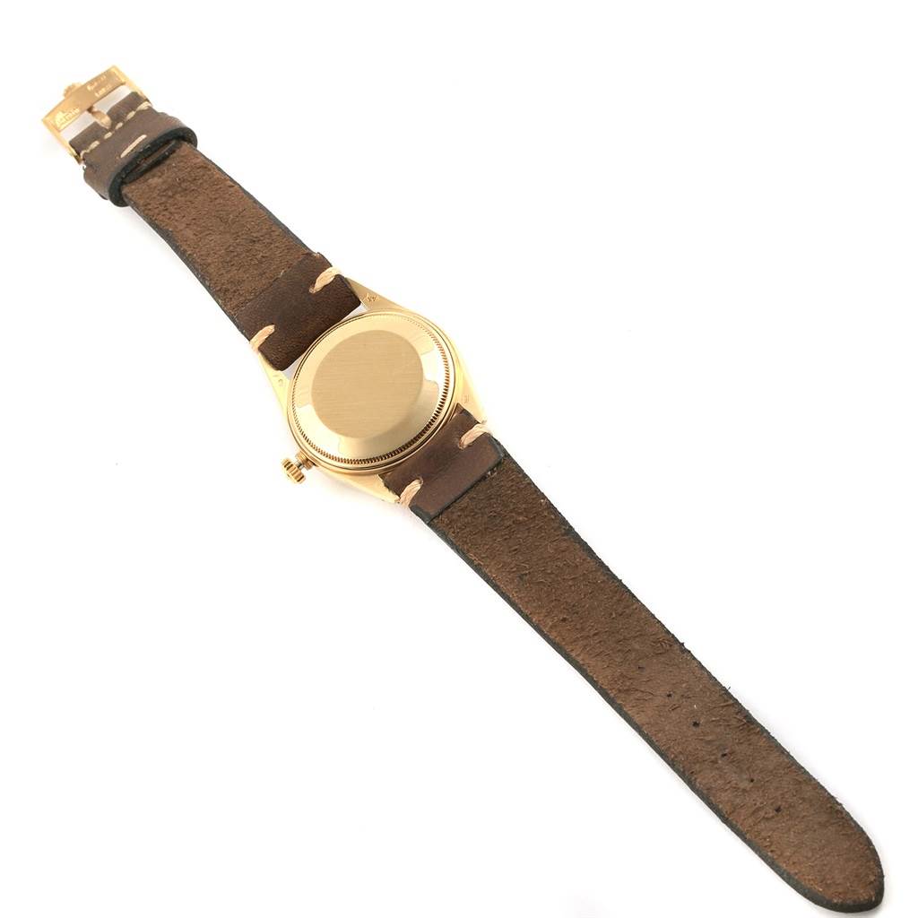 This image shows the back side of a Rolex President 15037 Men
s Yellow Gold Silver Dial 15037 Men
s Yellow Gold Silver Dial model watch and its brown leather strap.
