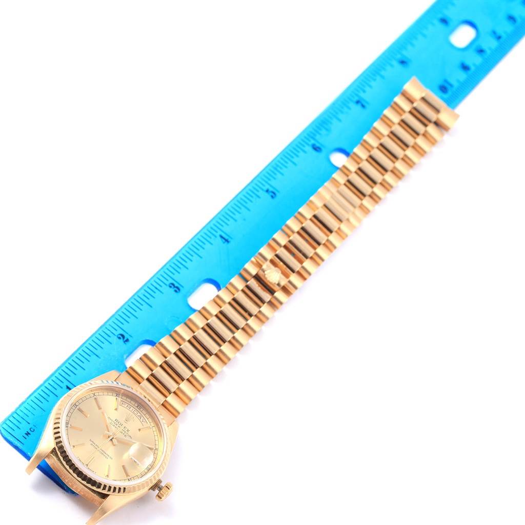 The image shows a Rolex President 18238 Men
s Yellow Gold Champagne Dial 18238 Men
s Yellow Gold Champagne Dial model watch in a horizontal angle, with the band extended and measured against a blue ruler.