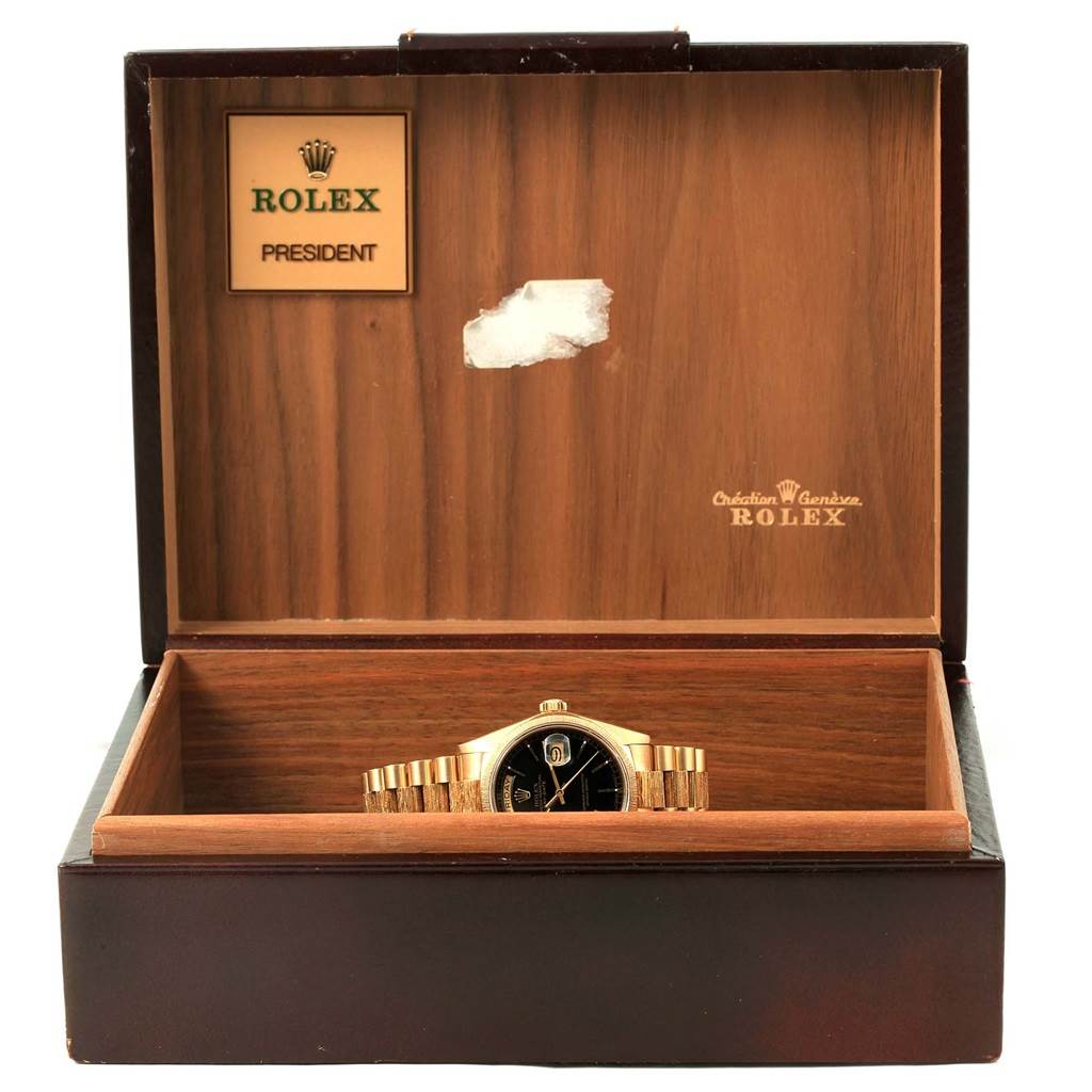 The image shows a Rolex President 18078 Men
s Yellow Gold Black Dial 18078 Men
s Yellow Gold Black Dial watch in its box, with the watch face and part of the band visible.