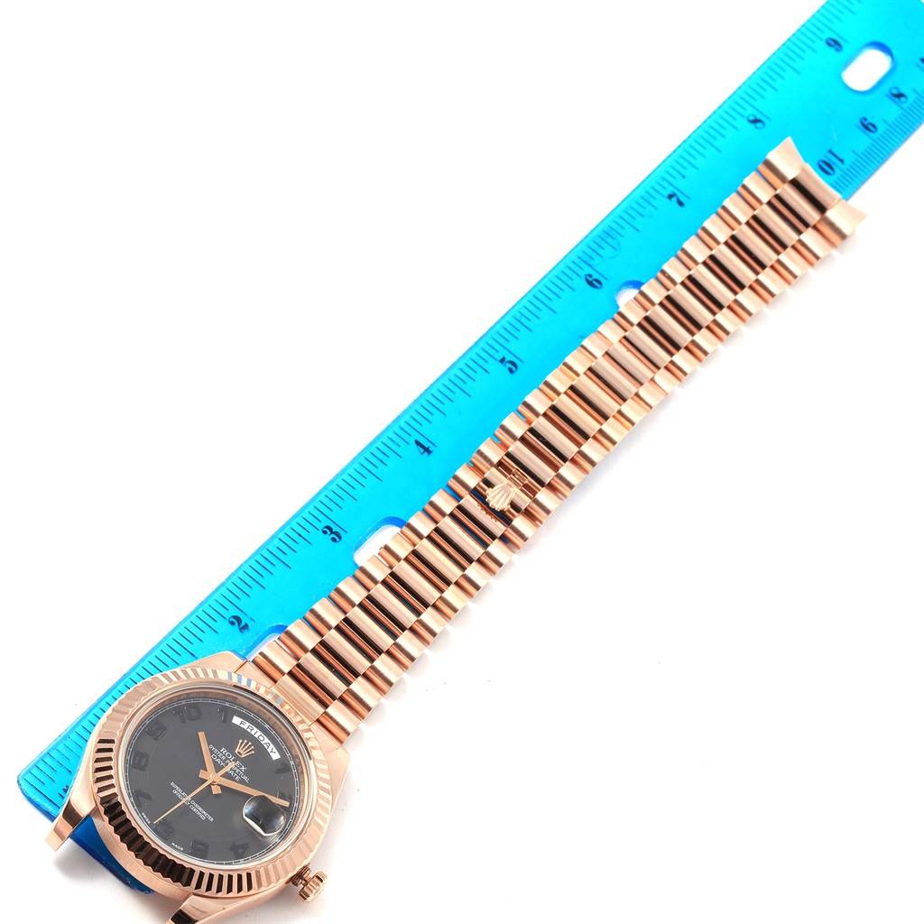 The Rolex President 218235 Men's Rose Gold Black Dial 218235 Men's Rose Gold Black Dial model watch is shown from a top-down angle with its face, bezel, and bracelet next to a ruler for scale.