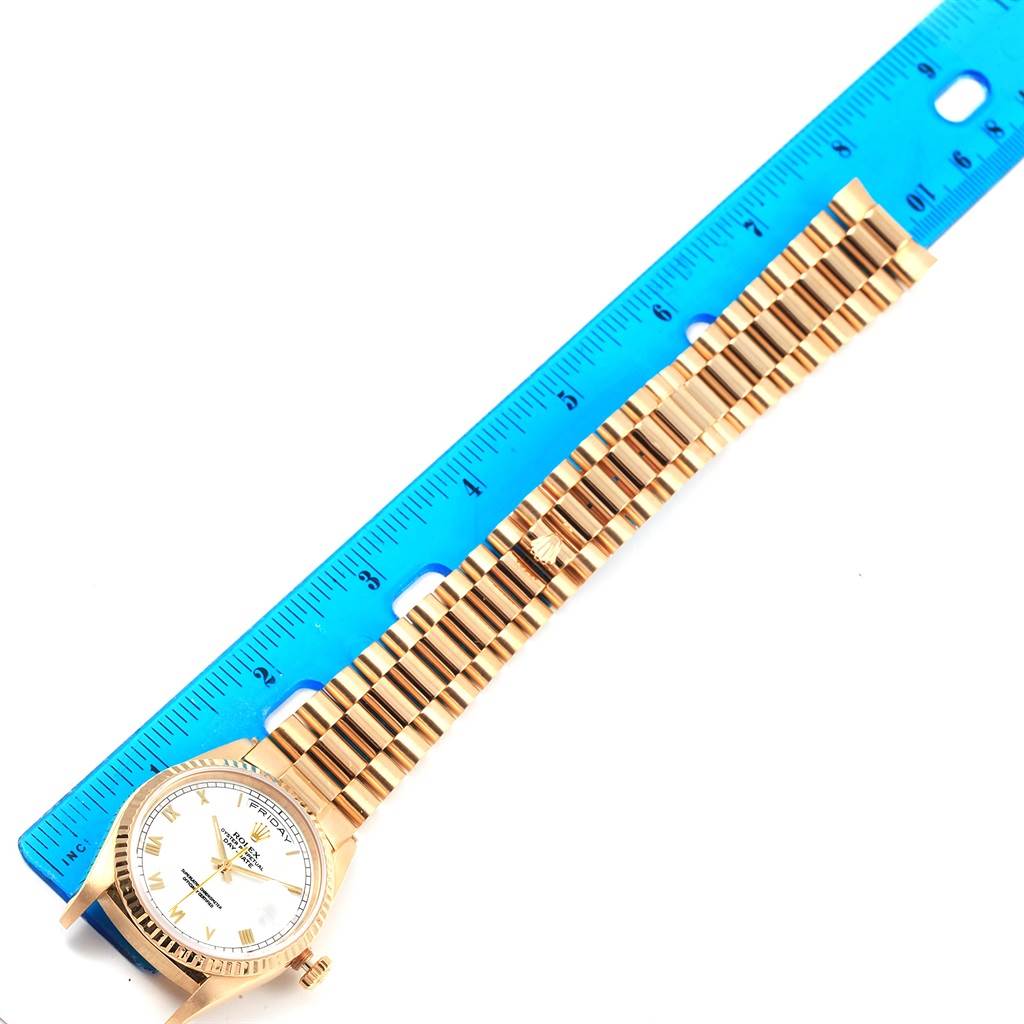 The Rolex President 18238 Men's Yellow Gold Champagne Dial 18238 Men's Yellow Gold Champagne Dial model watch is shown flat with its full length next to a blue ruler for scale.