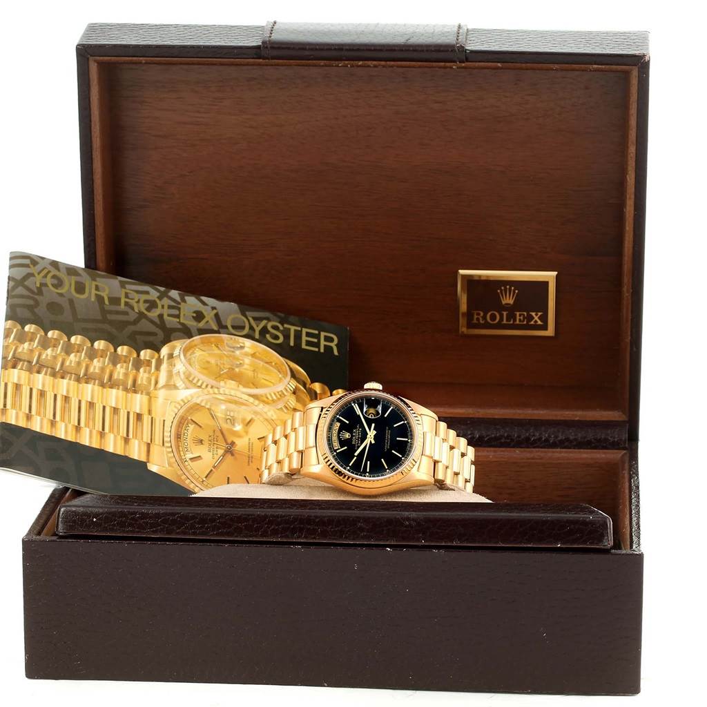 The image shows a Rolex President 18038 Men's Yellow Gold Black Dial 18038 Men's Yellow Gold Black Dial watch with a gold band and black dial inside its open wooden box.