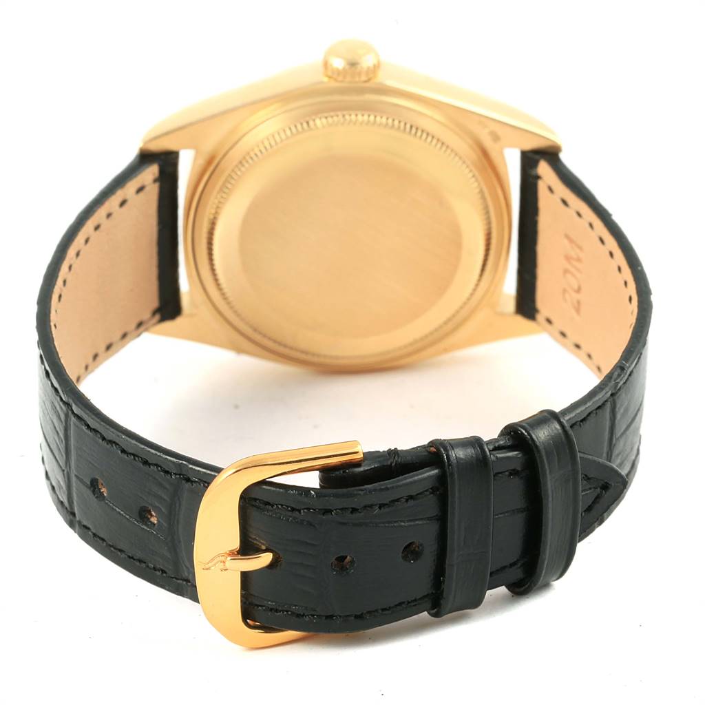 This image shows the back of the Rolex President 18038 Men
s Yellow Gold Beige Dial 18038 Men
s Yellow Gold Beige Dial watch case and its black leather strap with a gold buckle.