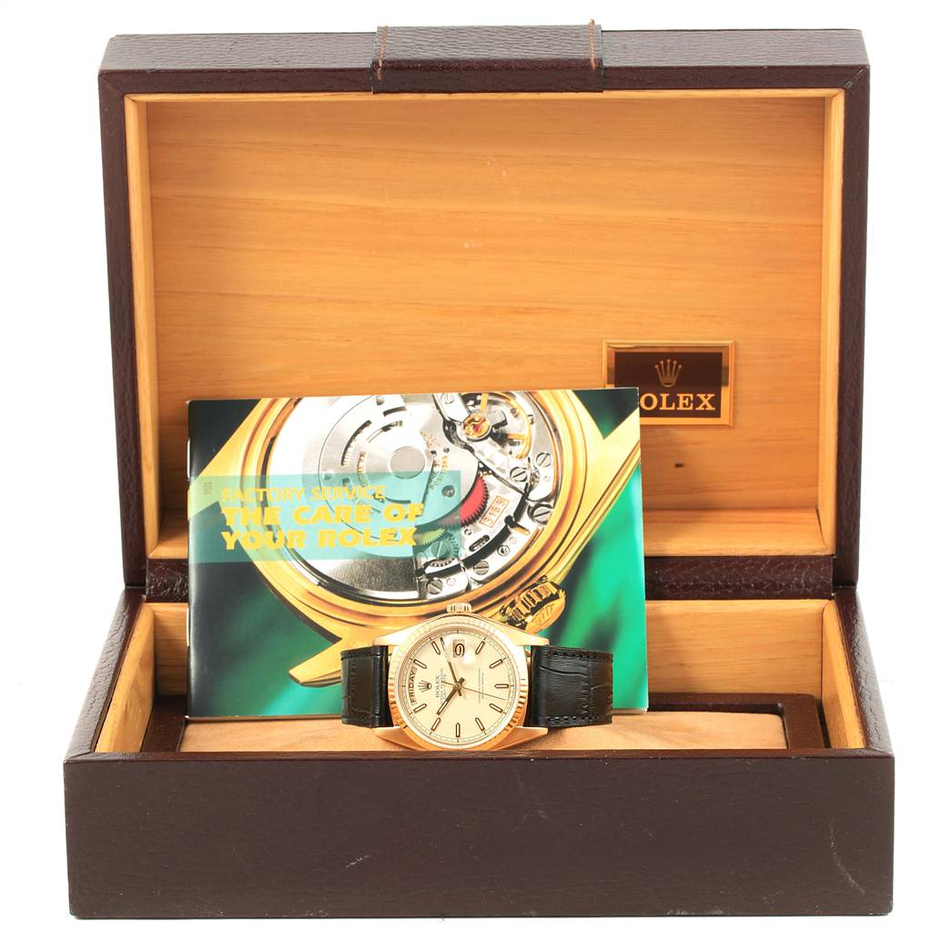The image shows a Rolex President 18038 Men
s Yellow Gold Beige Dial 18038 Men
s Yellow Gold Beige Dial model watch in its open box with an accompanying booklet inside.