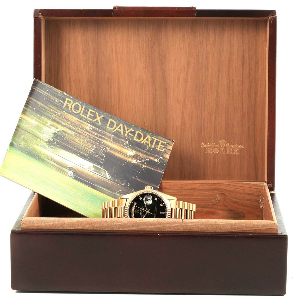 The watch, a Rolex President 18238 Men's Yellow Gold Black Dial 18238 Men's Yellow Gold Black Dial model, is shown partially inside an open box with a booklet beside it.