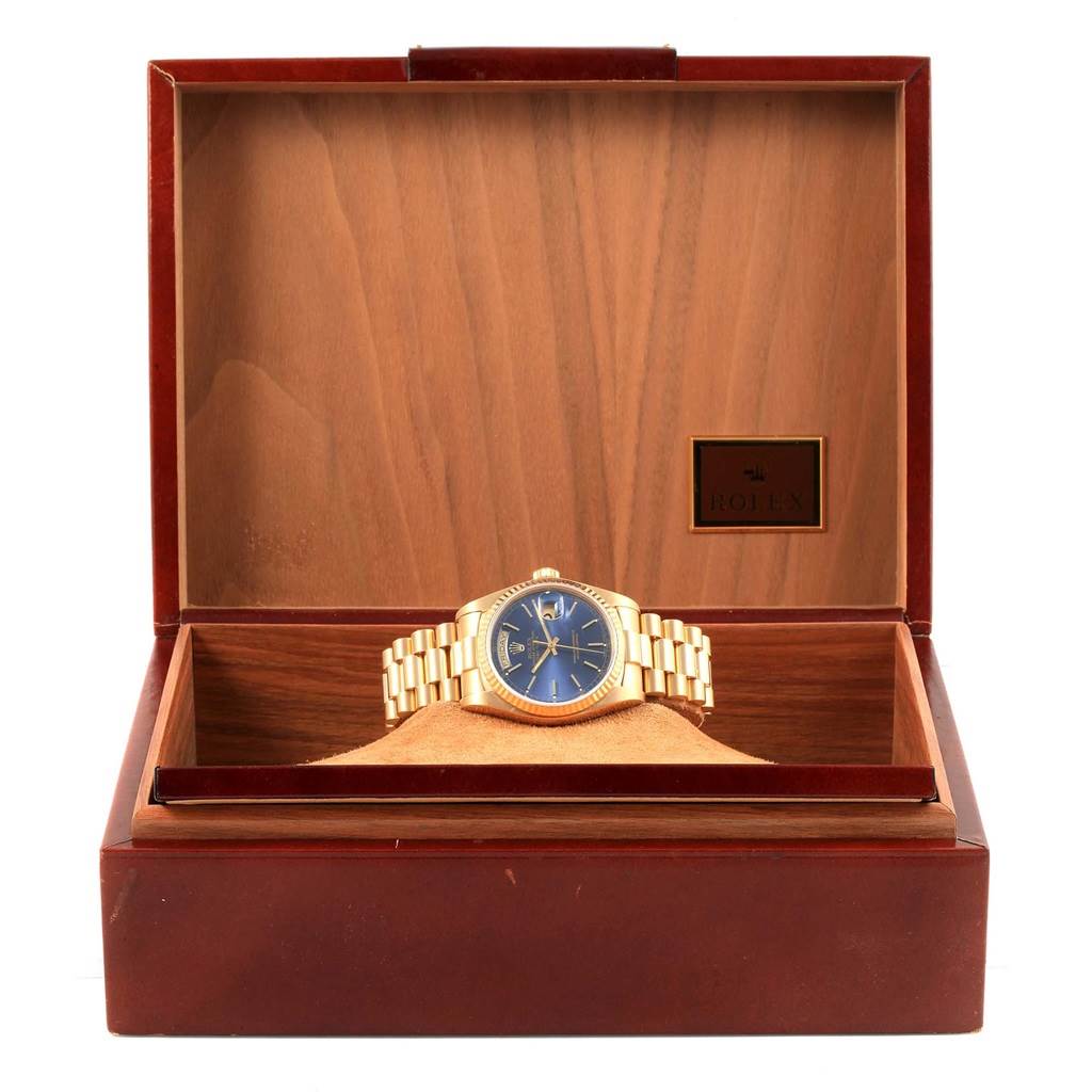 The Rolex President 18038 Men's Yellow Gold Blue Dial 18038 Men's Yellow Gold Blue Dial model watch is shown front-on in an open wooden box, displaying the face, bezel, and bracelet.