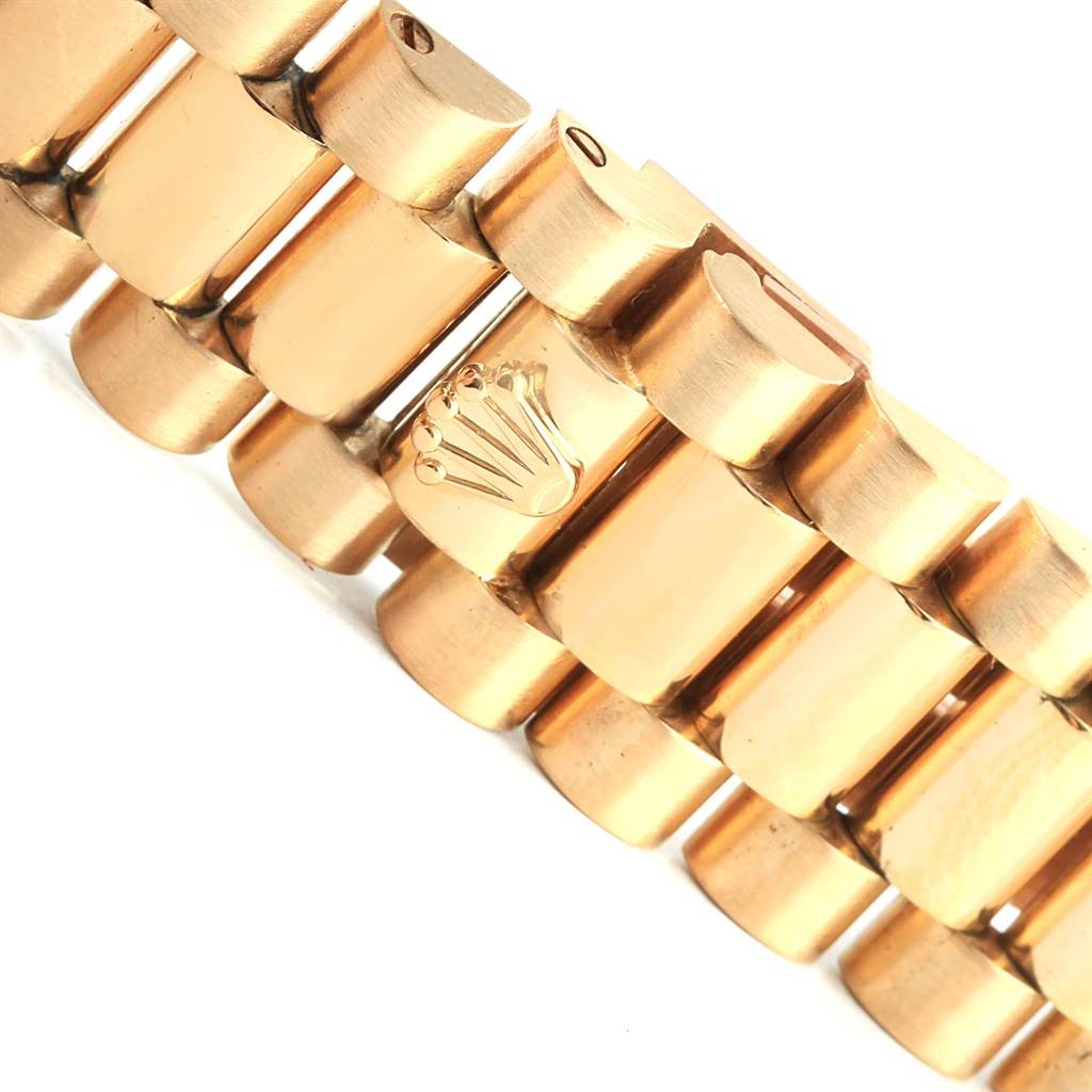 This image shows a close-up of the President bracelet from a Rolex watch, highlighting the gold links and the engraved Rolex crown logo.