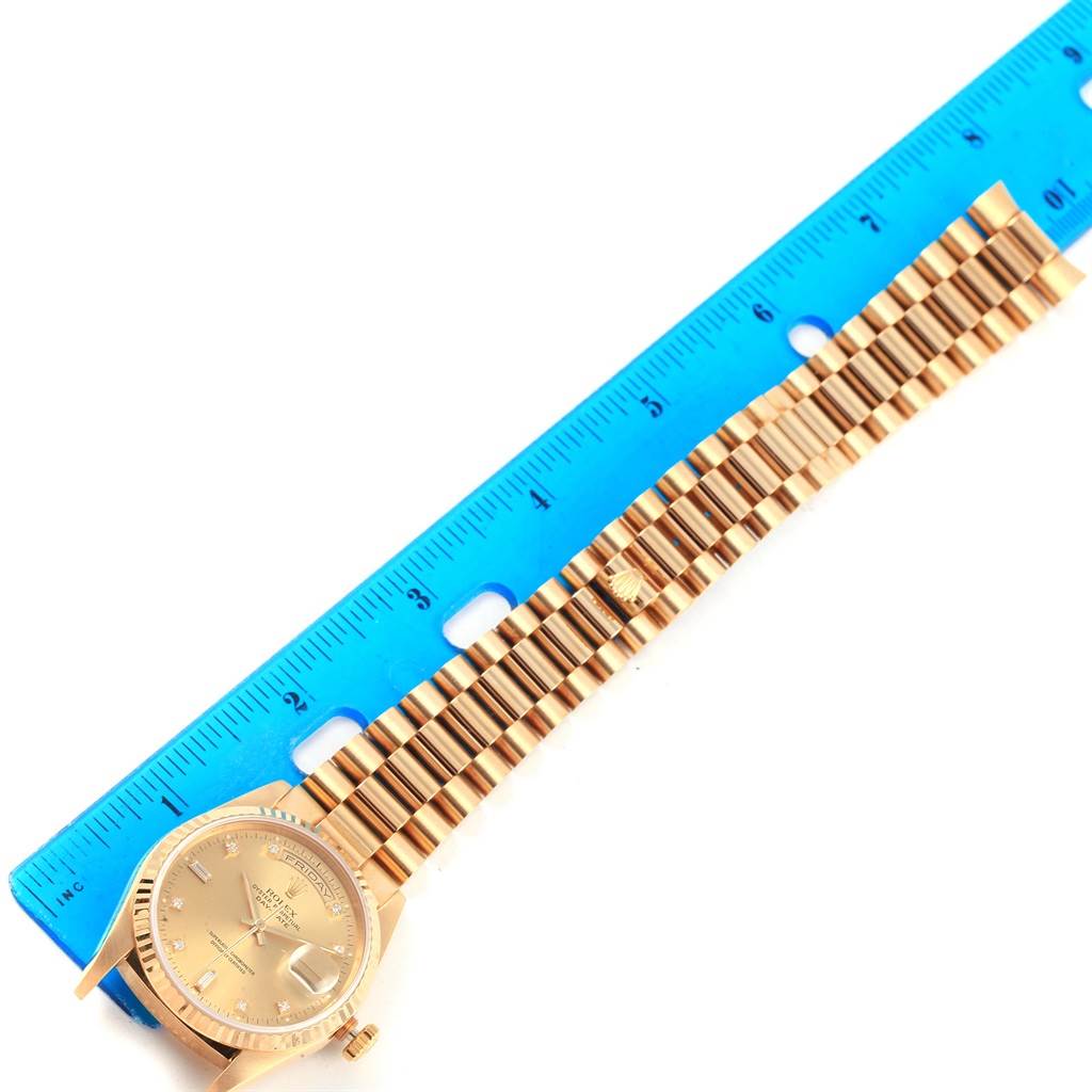 This image shows the Rolex President 18238 Men's Yellow Gold Champagne Dial 18238 Men's Yellow Gold Champagne Dial model watch laid flat, with a blue ruler measuring its length.