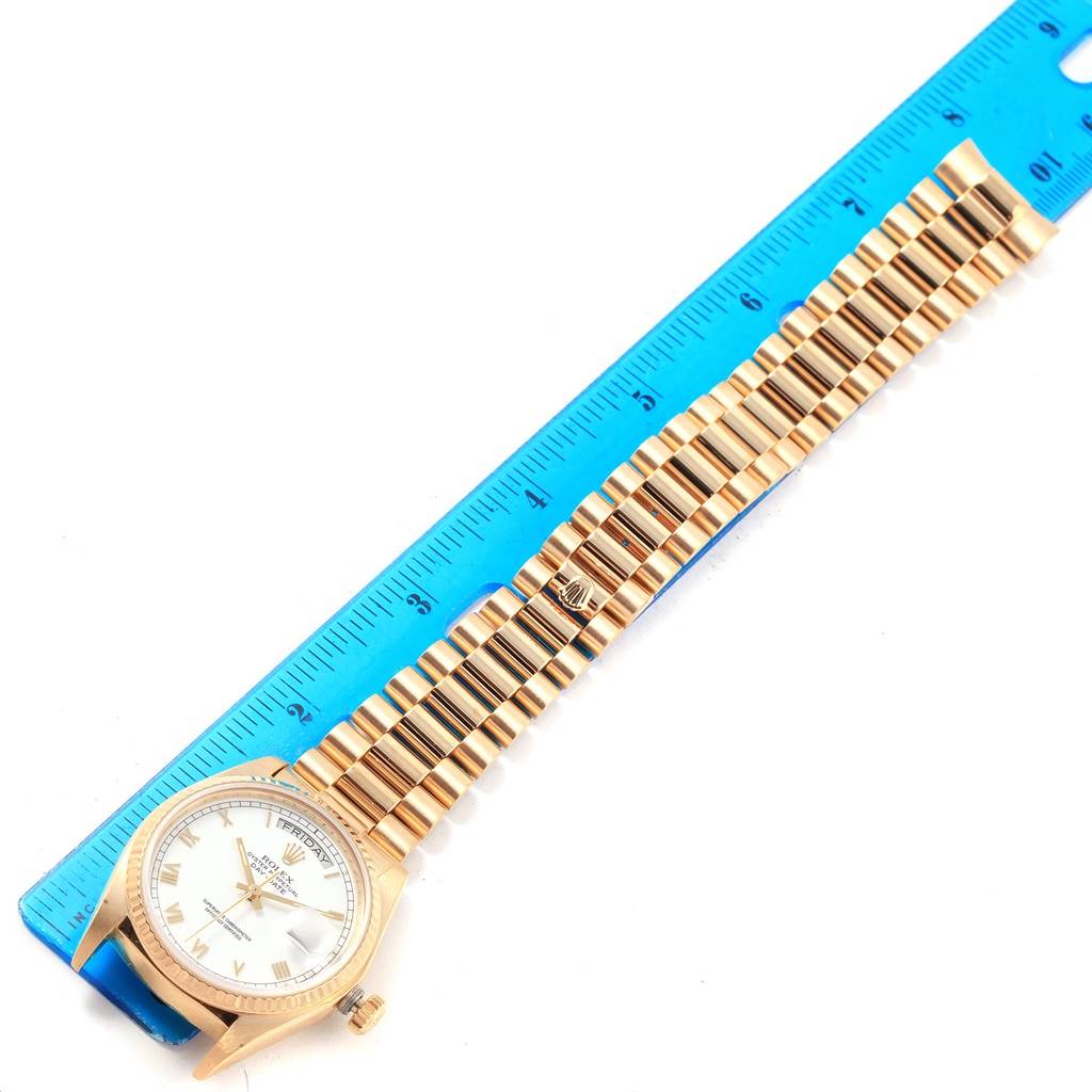 The image shows a Rolex President 18038 Men's Yellow Gold White Dial 18038 Men's Yellow Gold White Dial model watch, positioned flat with a blue ruler alongside the band for scale.