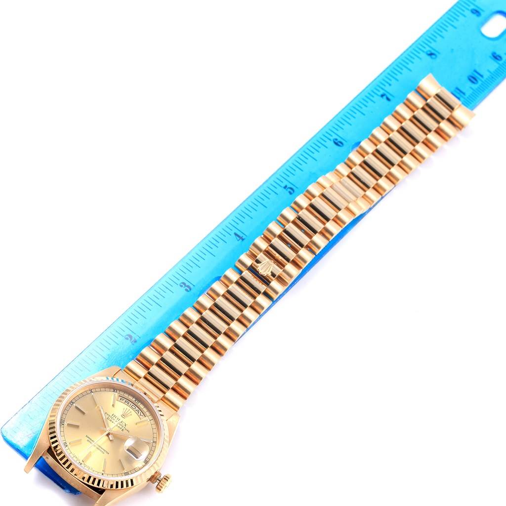 The Rolex President 18238 Men
s Yellow Gold Champagne Dial 18238 Men
s Yellow Gold Champagne Dial model watch is shown from a top view, showcasing its face, bezel, and entire bracelet next to a blue ruler.