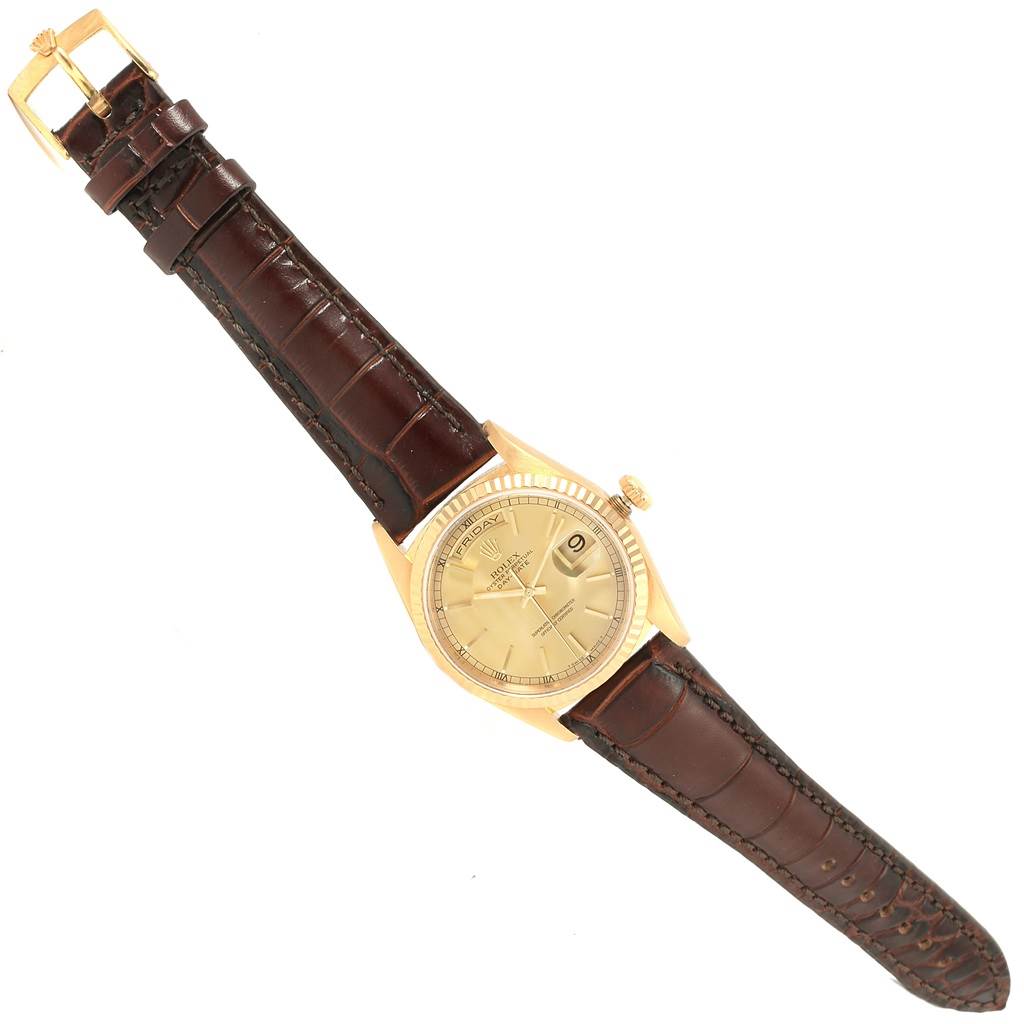 The image shows a President model Rolex watch with a brown leather strap, gold case, crown, and a champagne dial with a day-date indicator.
