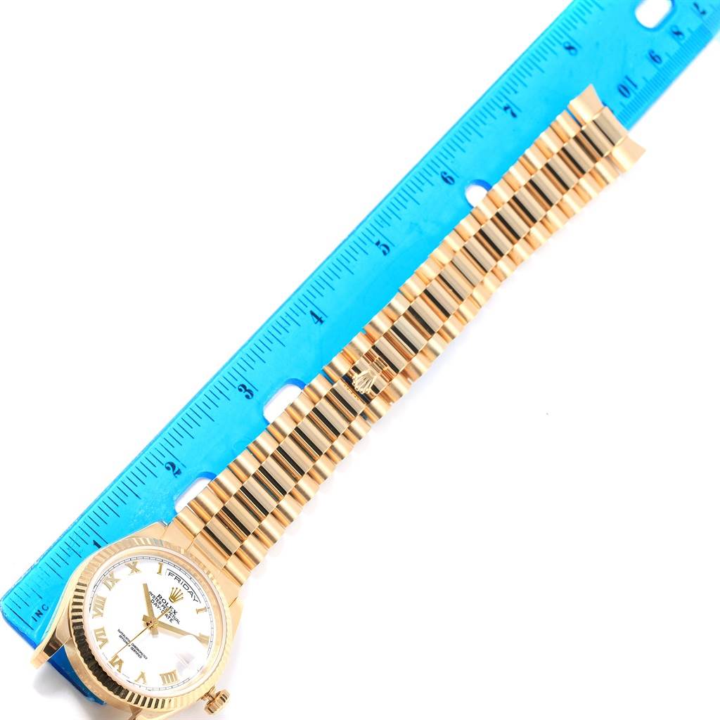 The image shows a Rolex President 118238 Men's Yellow Gold White Dial 118238 Men's Yellow Gold White Dial model watch, angled from above, with its face, crown, and bracelet visible next to a blue ruler.