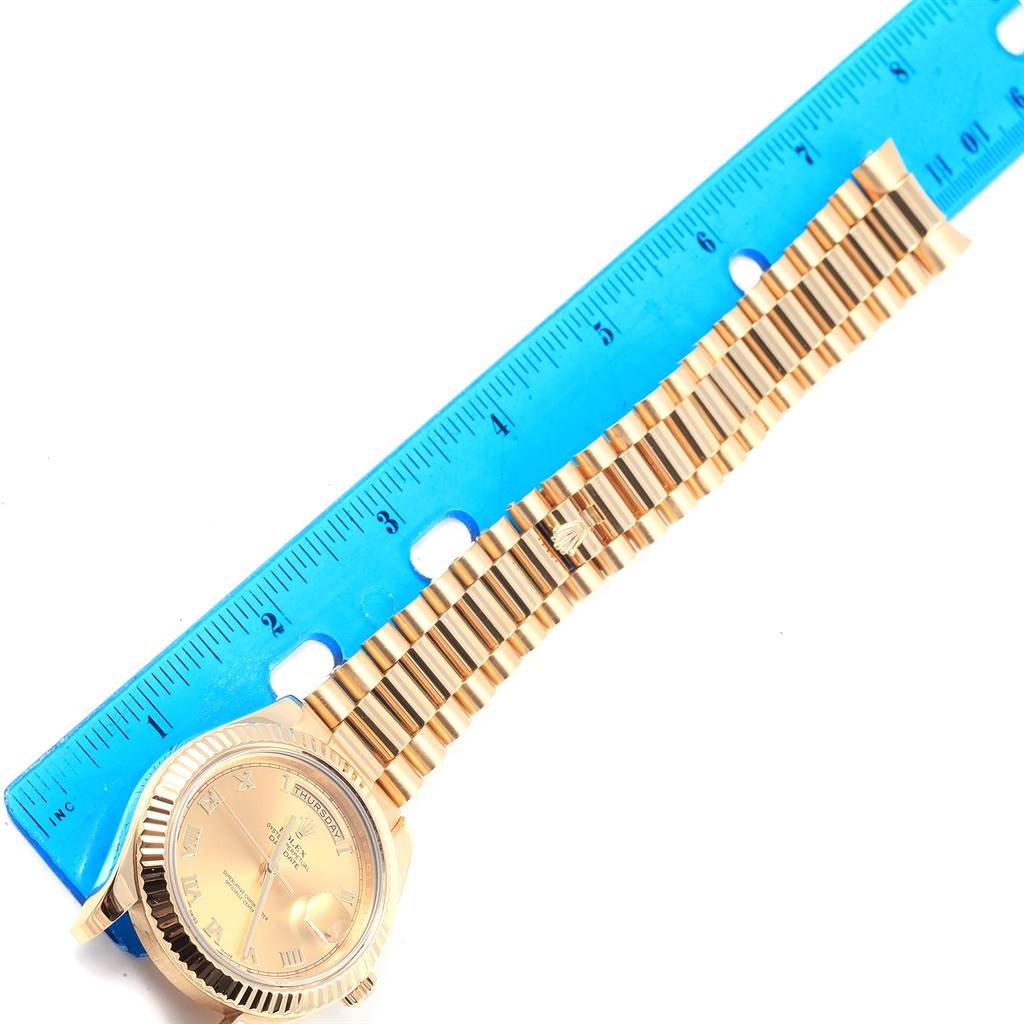 The image shows a top-down view of a gold Rolex President 218238 Men's Yellow Gold Champagne Dial 218238 Men's Yellow Gold Champagne Dial model watch next to a blue ruler.