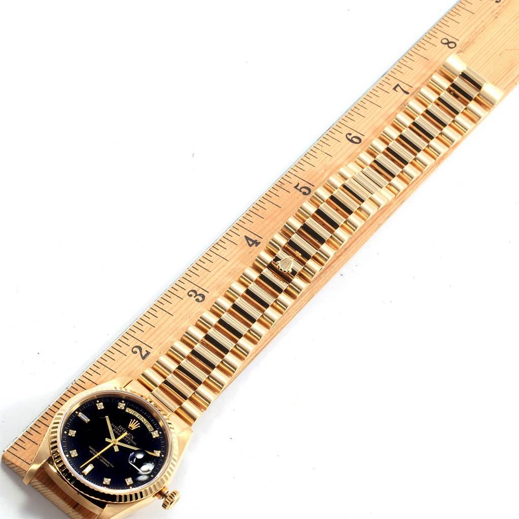 This image shows a Rolex President 18238 Men's Yellow Gold Black Dial 18238 Men's Yellow Gold Black Dial model watch laid flat next to a ruler, highlighting its face and bracelet.