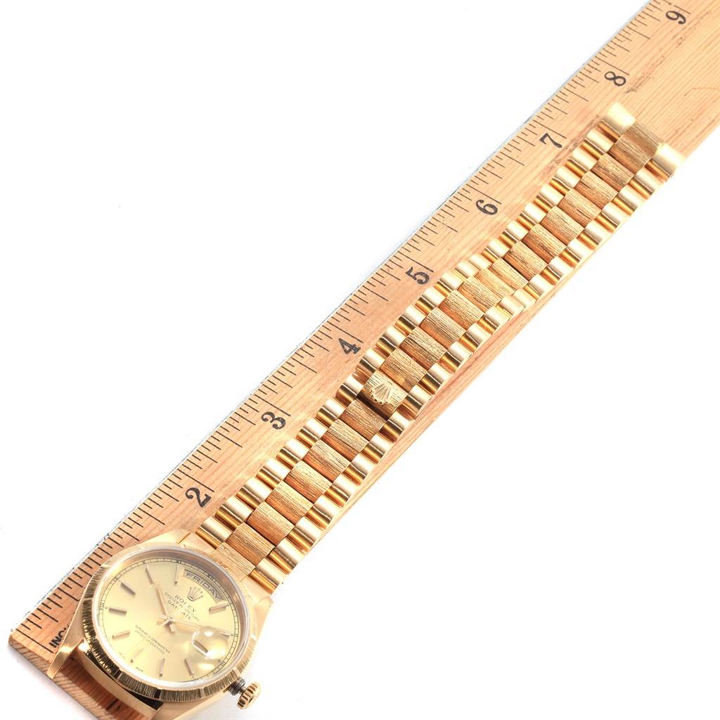 The Rolex President 18248 Men's Yellow Gold Champagne Dial 18248 Men's Yellow Gold Champagne Dial model watch is shown from a top-down angle, featuring the watch face and band beside a wooden ruler.