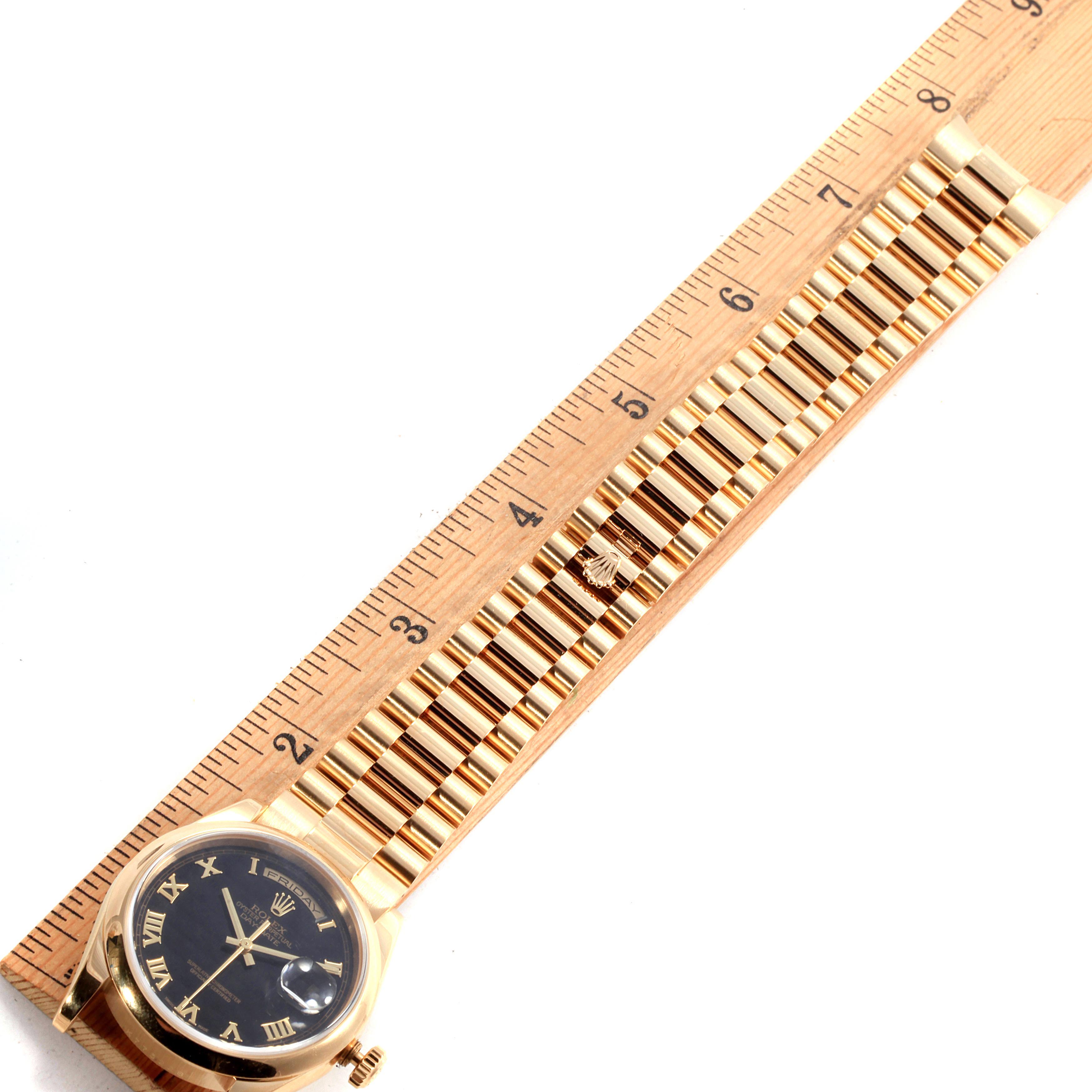The image shows a top-down view of a Rolex President 118208 Men
s Yellow Gold Black Dial 118208 Men
s Yellow Gold Black Dial watch, including the face, case, and part of the bracelet next to a ruler.