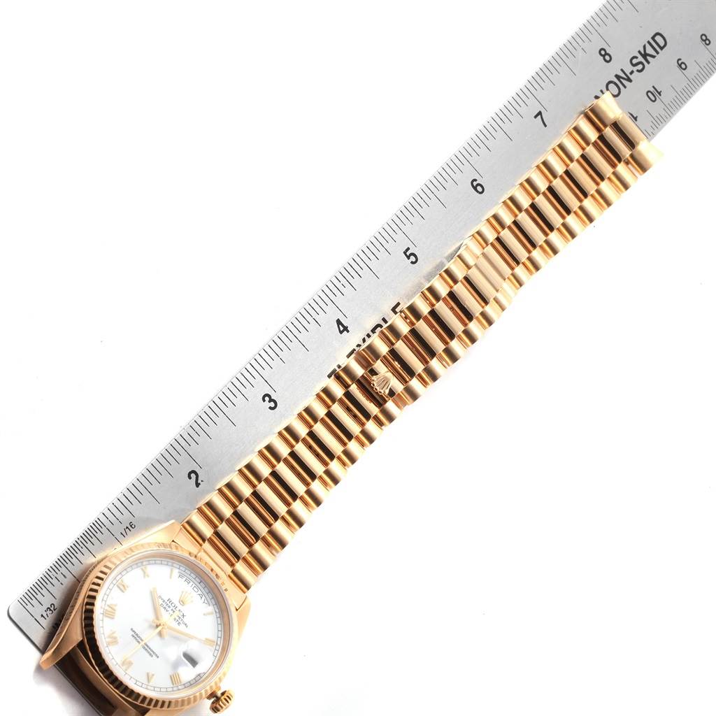 The image shows a Rolex President 18238 Men
s Yellow Gold White Dial 18238 Men
s Yellow Gold White Dial model watch with a gold bracelet laid flat alongside a ruler.