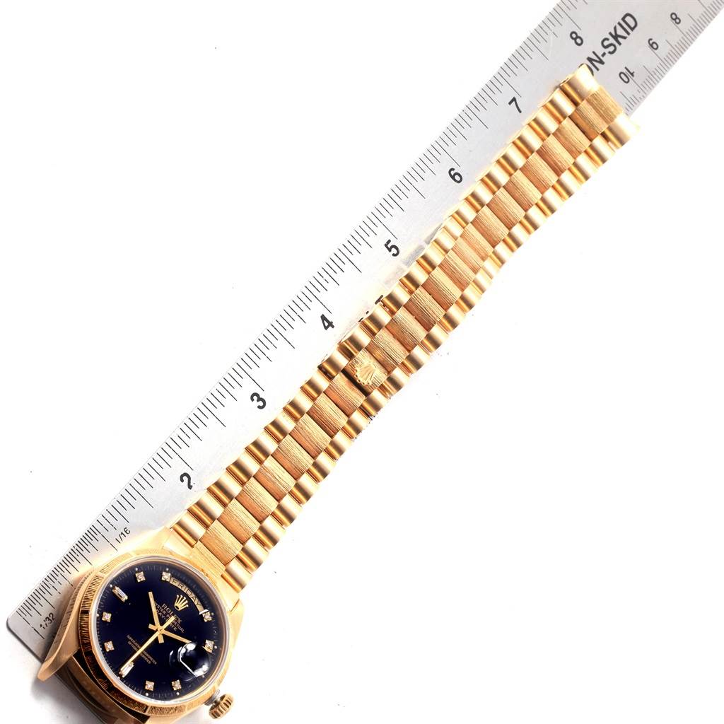 The Rolex President 18078 Men's Yellow Gold Black Dial 18078 Men's Yellow Gold Black Dial model watch is shown from an overhead angle, displaying the face, bracelet, and part of the clasp alongside a ruler.