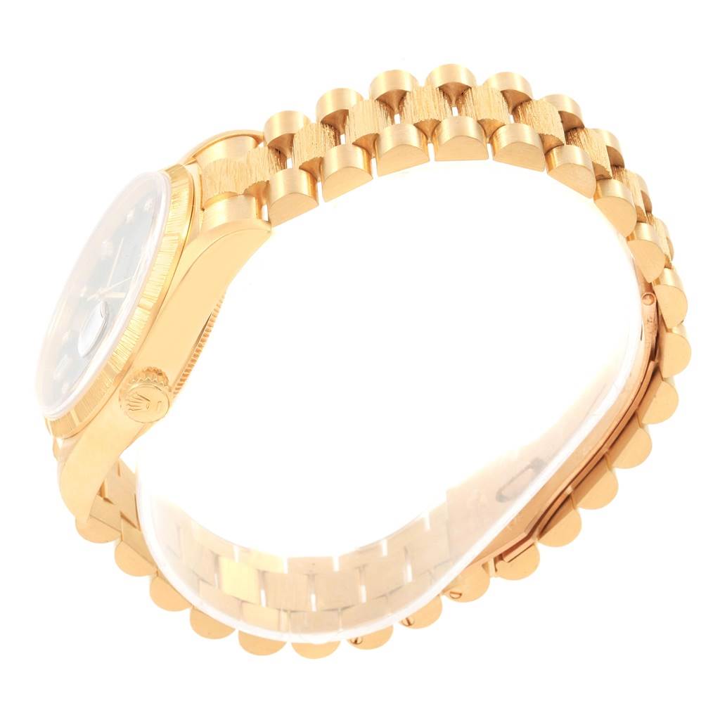 The image shows a side view of the Rolex President 18308 Men
s Yellow Gold Black Dial 18308 Men
s Yellow Gold Black Dial watch, highlighting its gold bracelet and partially visible face and crown.